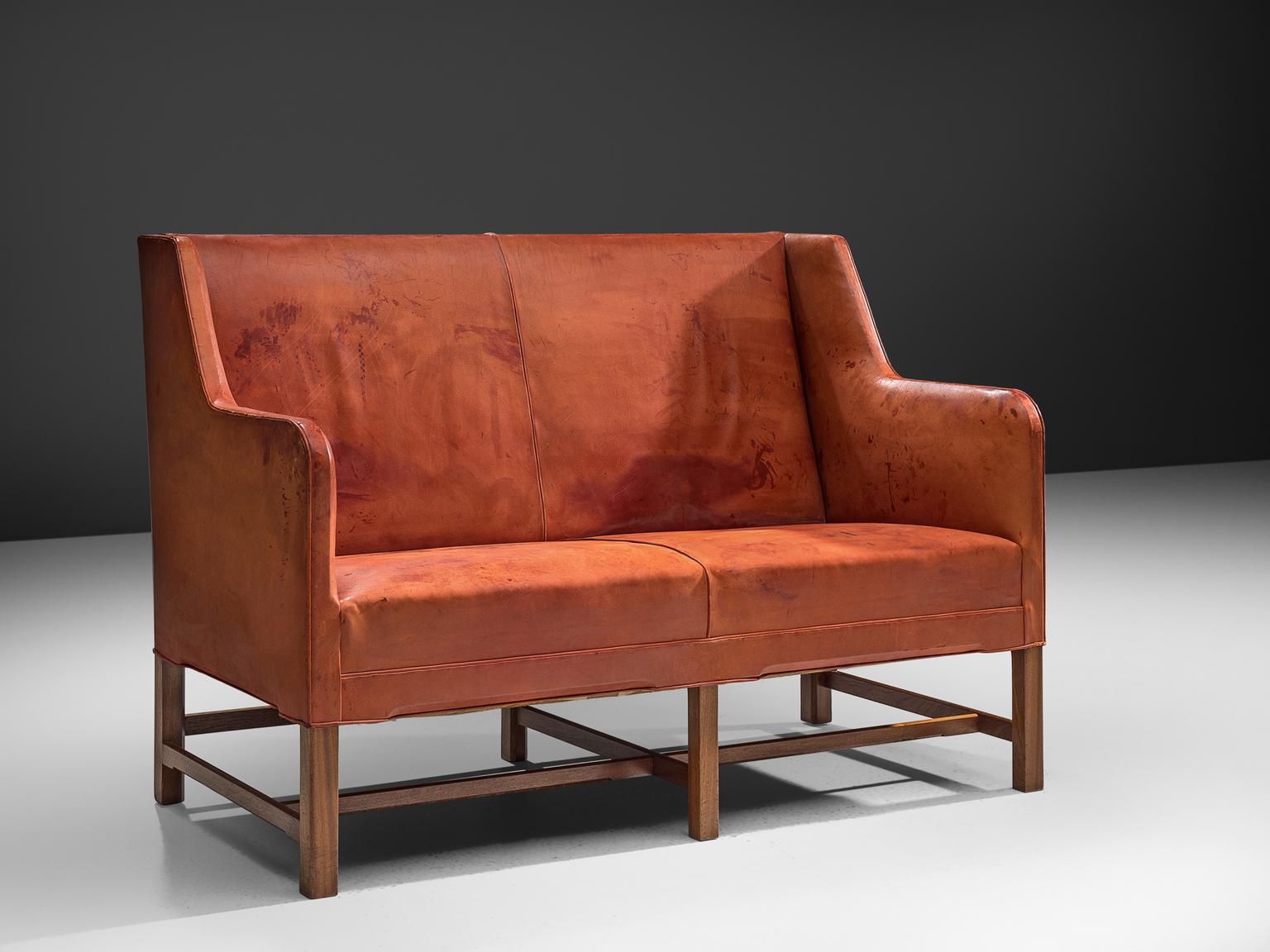 Kaare Klint for Rud Rasmussen two-seat settee, in red cognac leather and teak legs, Denmark, 1930s.

Classic and elegant Scandinavian custom-made two-seat settee by Kaare Klint for manufacturer Rud Rasmussen. The piece is upholstered with