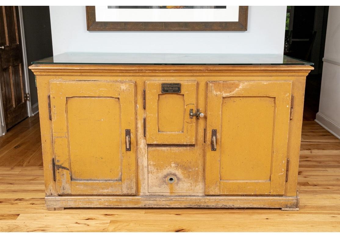 An early 20th century beer cooler in original mustard paint from Switzerland. Large and very solid construction with Three doors all having the original Iron/Steel door-pulls in working condition, the interior with Tin Lining and one fixed shelf.