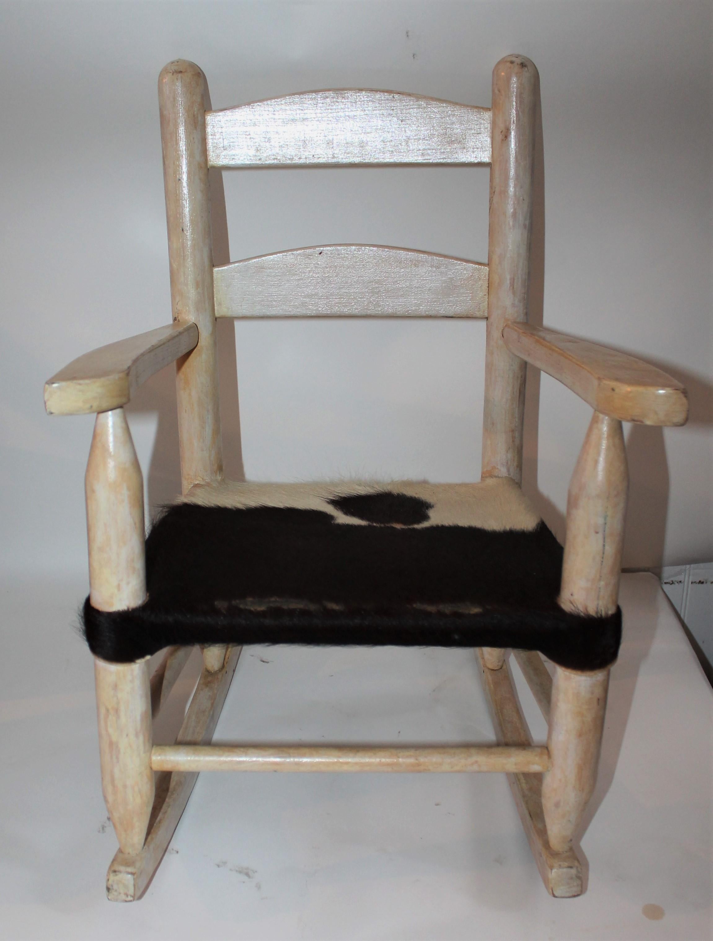 This fine and sturdy original white painted children's rocking chair is in fine condition and has a upholstered seat in cow skin.