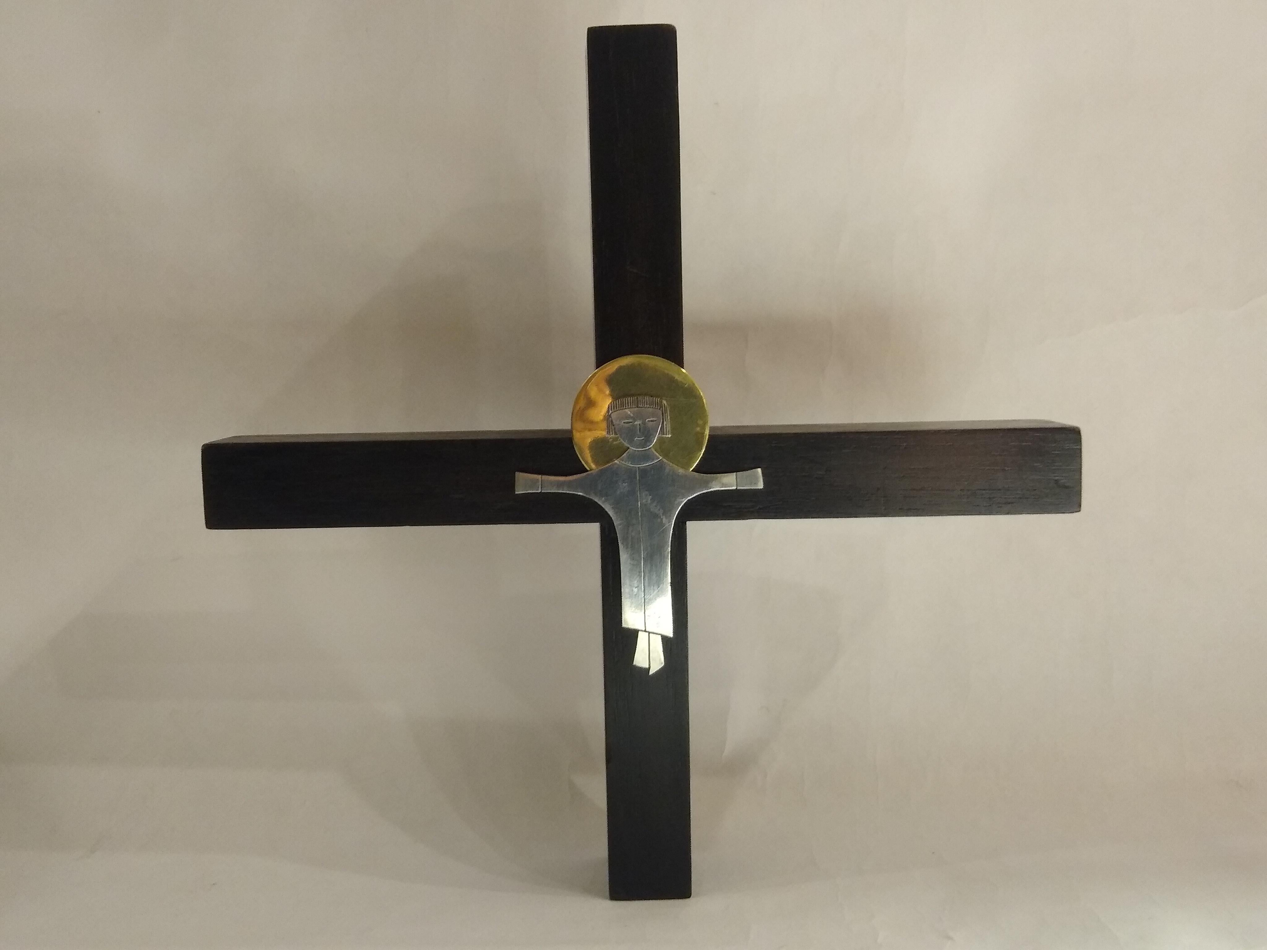 Skulptur, die ein Kreuz mit einer stilisierten, skurrilen Darstellung von Christus auf dunklem Holz, Sterling und Messing darstellt. Sie wurde von 