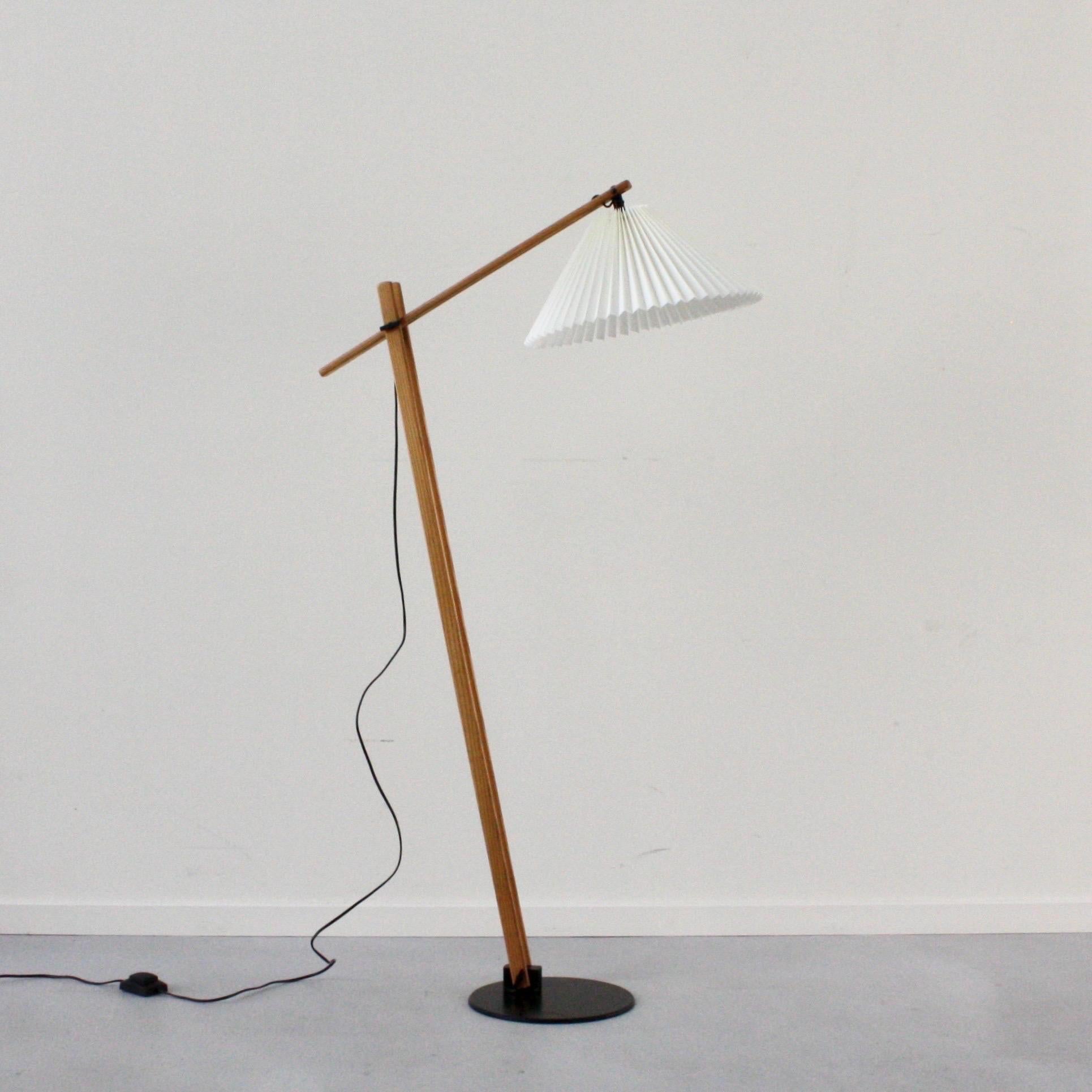 An oak wood floor lamp desinged by Mads Caprani in the 1970s for Caprani Light. This style is a rare find in excellent condition. It features a black metal base, adjustable oak stems and a light colored fabric shade. 

* An oak wood floor lamp with