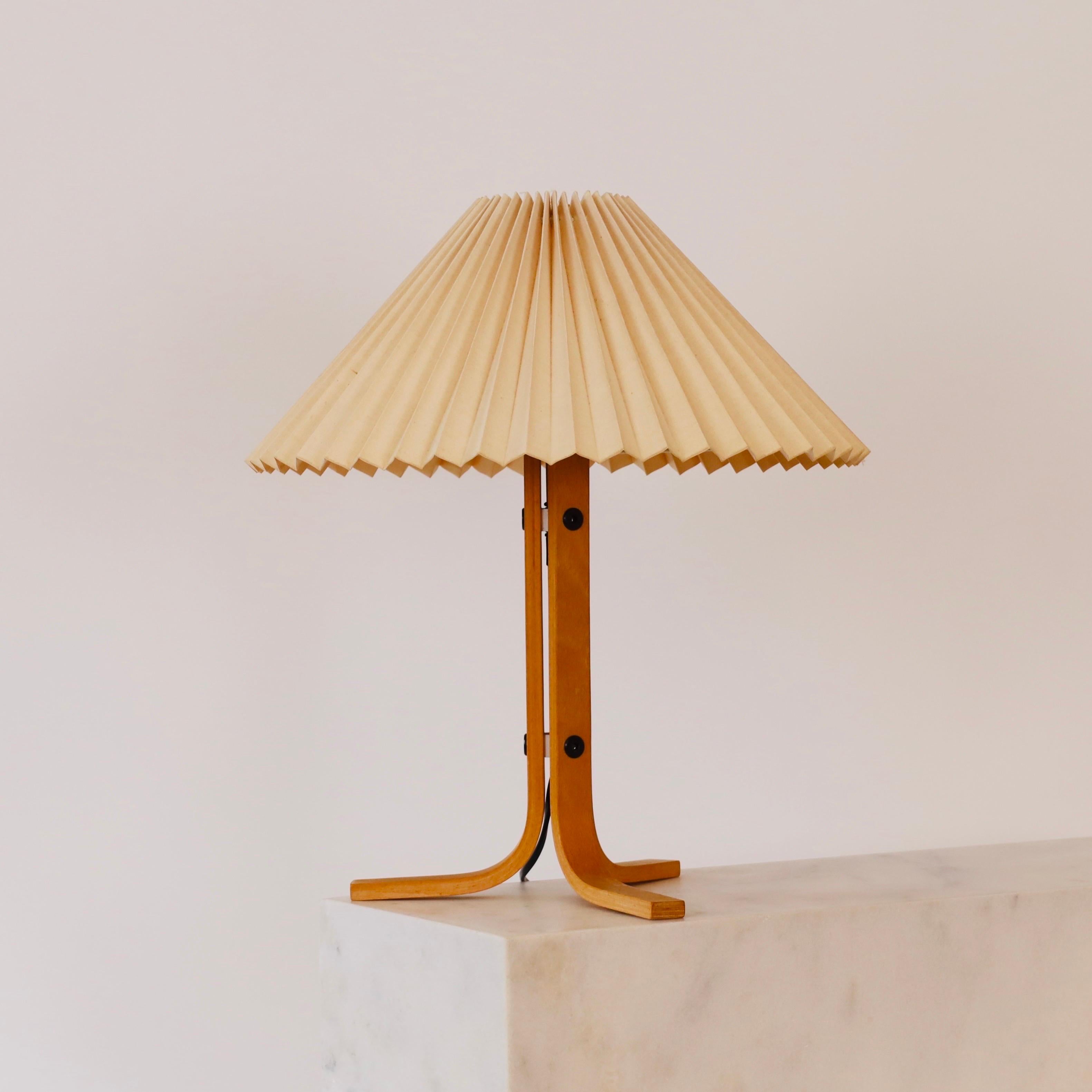 A beech wood tripod desk lamp designed by Mads Caprani in the 1970s for Caprani Light. A rare find for a beautiful home.

* A  tripod desk lamp in bend beech veneer with a pleated light beige fabric shade
* Designer: Mads Caprani
* Model: 223
*