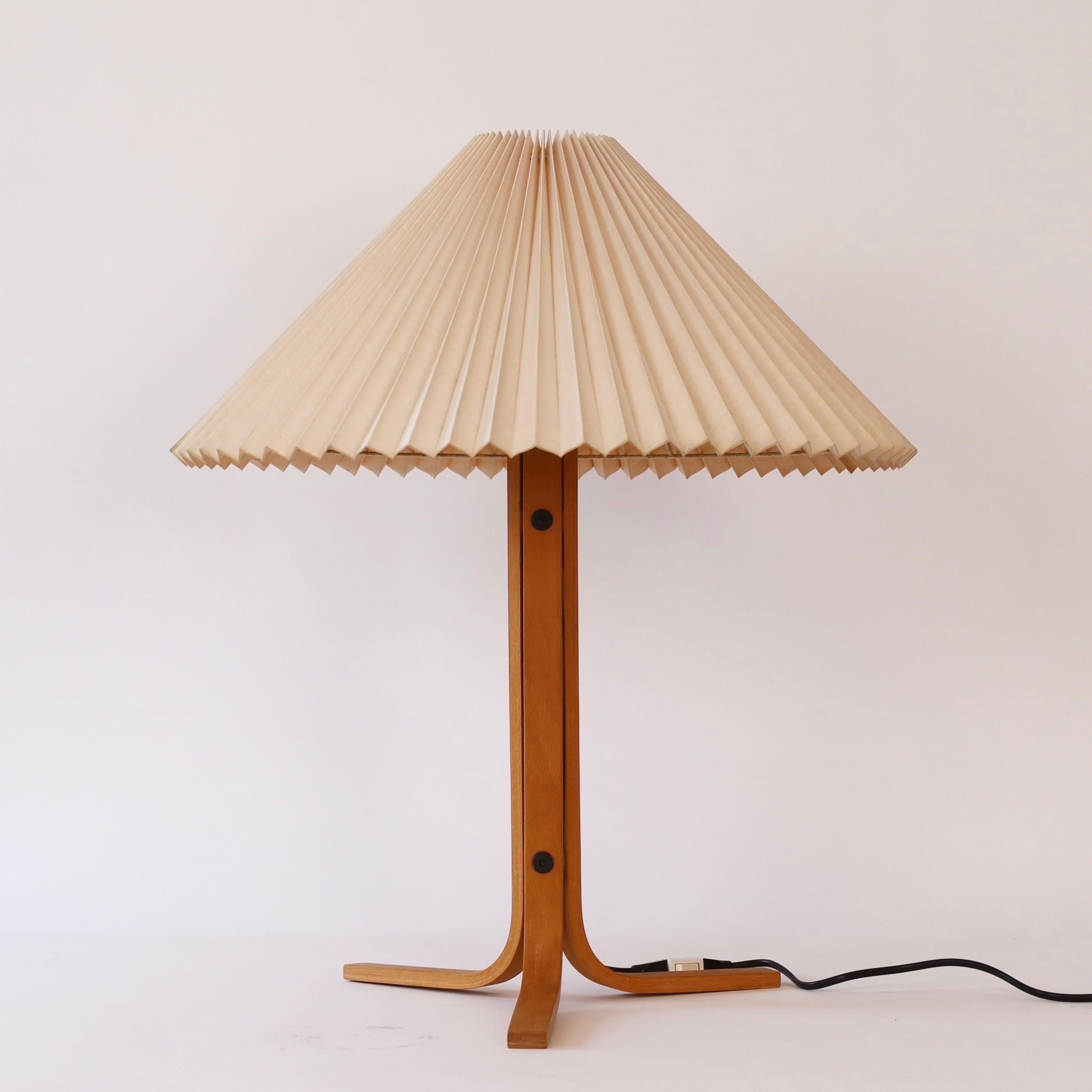 A beech wood tripod desk lamp designed by Mads Caprani in the 1970s for Caprani Light. A rare find for a beautiful home.

* A  tripod desk lamp in bend beech veneer with a pleated light beige fabric shade
* Designer: Mads Caprani
* Model: 221
*