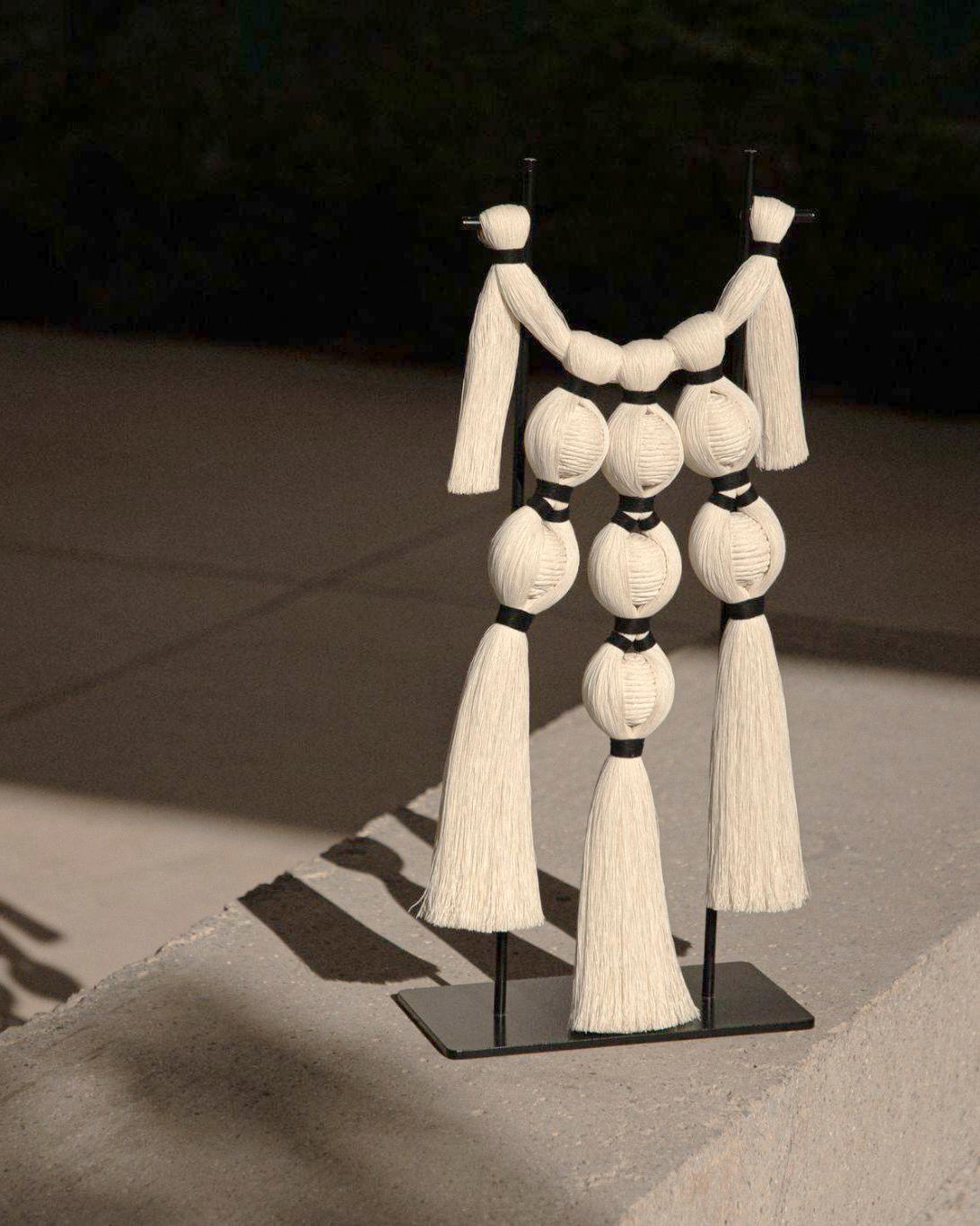 Questa splendida scultura è realizzata con fili di cotone grezzo intrecciati tra loro in modo da assomigliare a una serie di occhi, arricchiti da nappe su una base di metallo. La Desert Eyes Space Jewelry Sculpture è un pezzo d'arte contemporanea