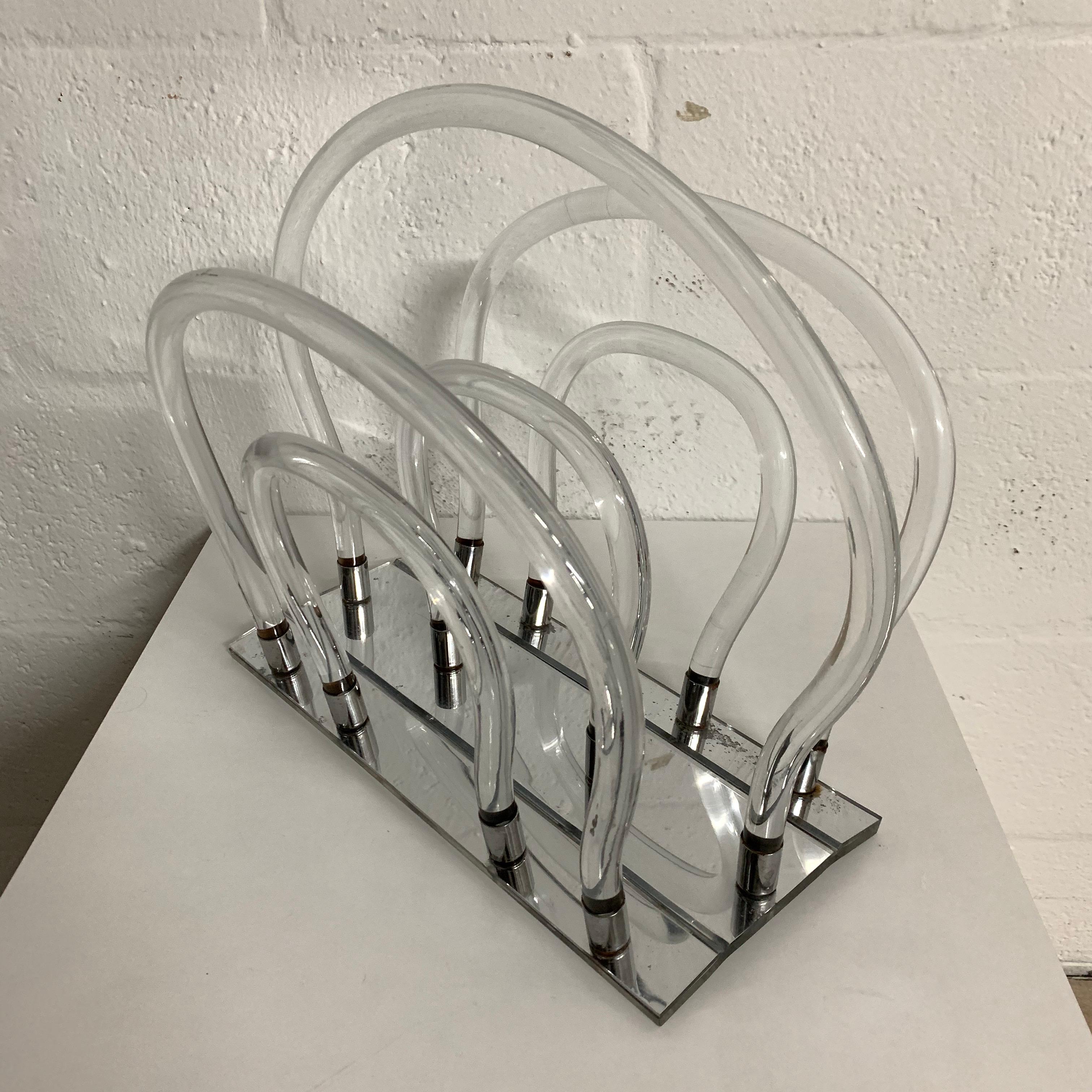 Magazine rack or stand rendered in clear bent Lucite and chrome with a mirrored Lucite base by, Dorothy Thorpe, 1960s.