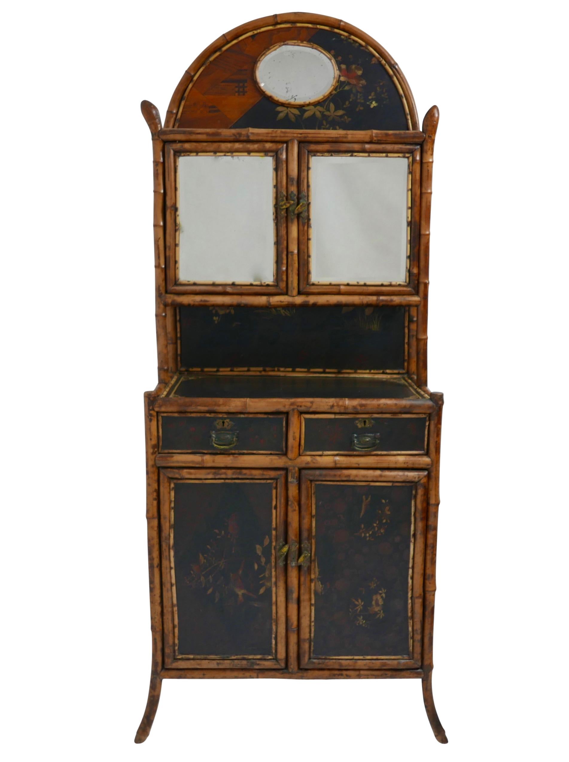 Completely original Bamboo cabinet with lacquer panels, beveled glass mirrors, embossed paper panels on the sides bamboo root finials.
The arched top set with demi lune lacquer panel and oval beveled glass mirror above two beveled glass doors then