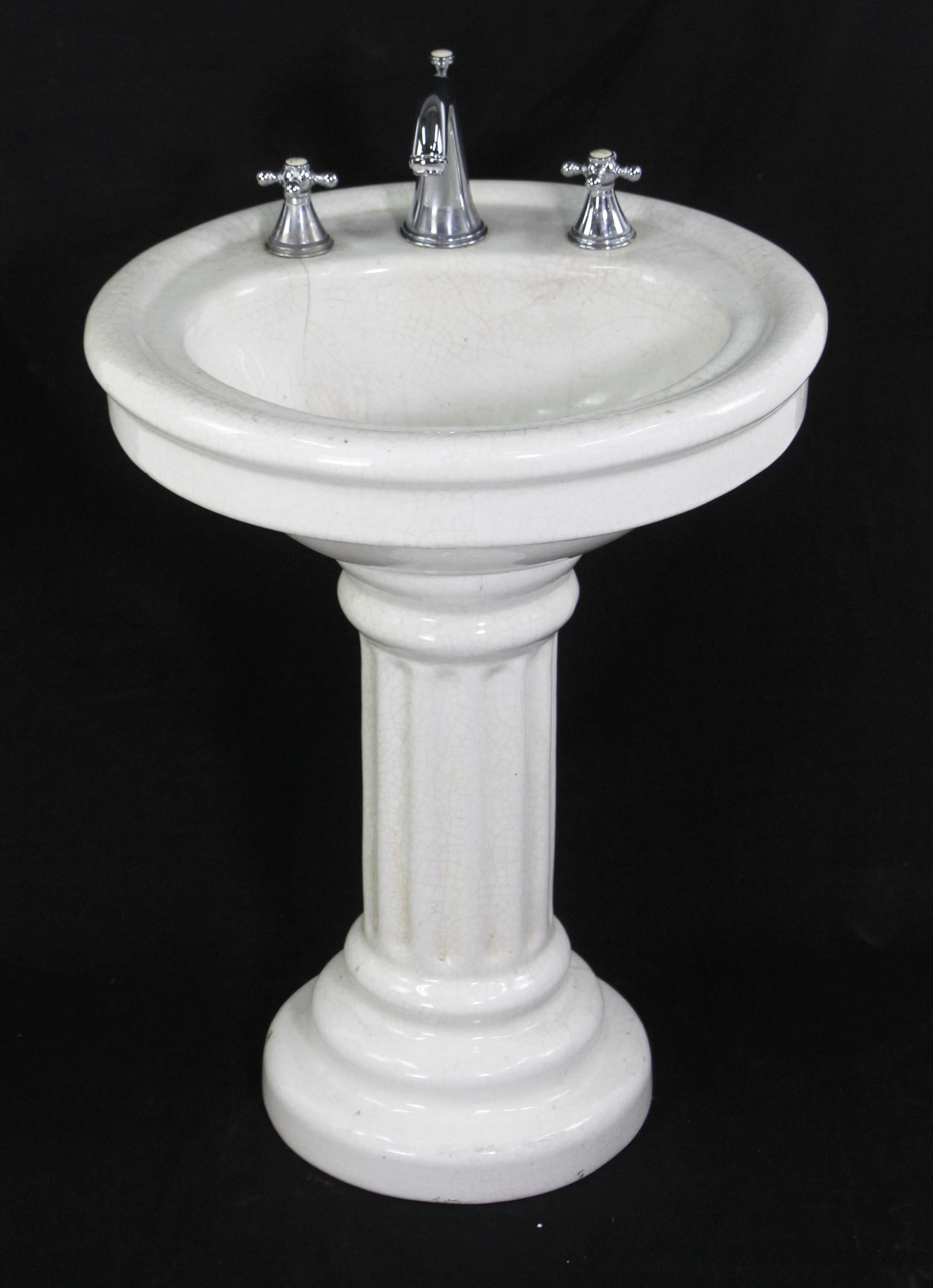 Antique early 20th century oval pedestal sink manufactured out of glazed earthenware. Pedestal features a fluted column. Glazing has crackling throughout. Minor chips. Please see the photos. Small quantity available at time of posting. Please
