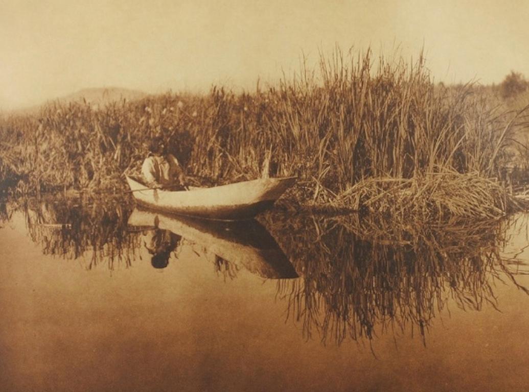 Presented is a beautiful photogravure showing a Klamath man hunting from a dugout canoe. This image is Plate 458 from Volume 13 of Edward Curtis' epic project The North American Indian. The photogravure was published in 1923 by Suffolk Engr. Co., in