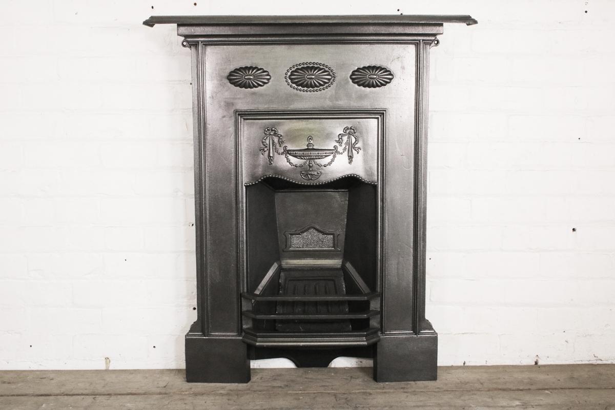 Original Edwardian cast iron bedroom fireplace with three rosettes to the frieze and a classical urn and drapes to the canopy, circa 1900. 

This grate has been finished the traditional black grate polish, leaving a gun metal / pewter shine.