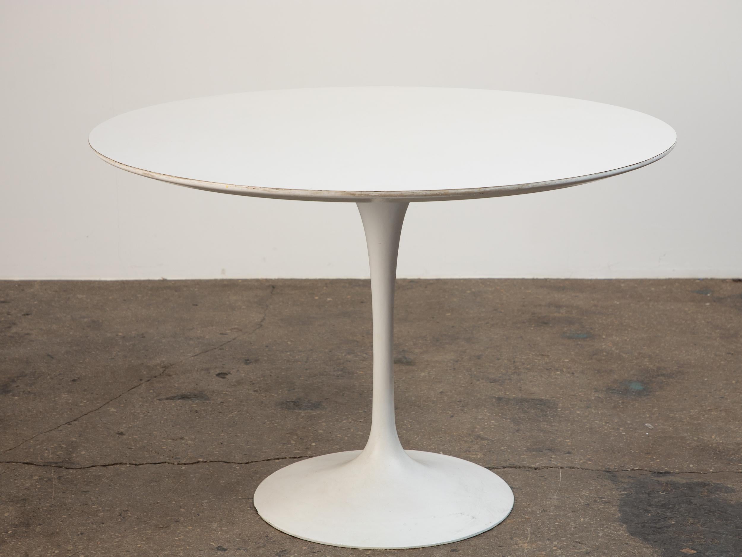 Table de salle à manger tulipe emblématique, conçue par Eero Saarinen pour Icone. Elegant dans sa simplicité, ce design classique du milieu du siècle présente un plateau en linoléum blanc durable associé à une base à piédestal lesté. La base, qui