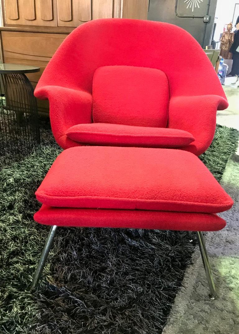Iconic and classic. This sculpturally designed, original womb chair and accompanying ottoman is by famed Finnish / American designer Eero Saarinen and produced by Knoll. The chair and ottoman both retain their original red bouclé fabric (recently