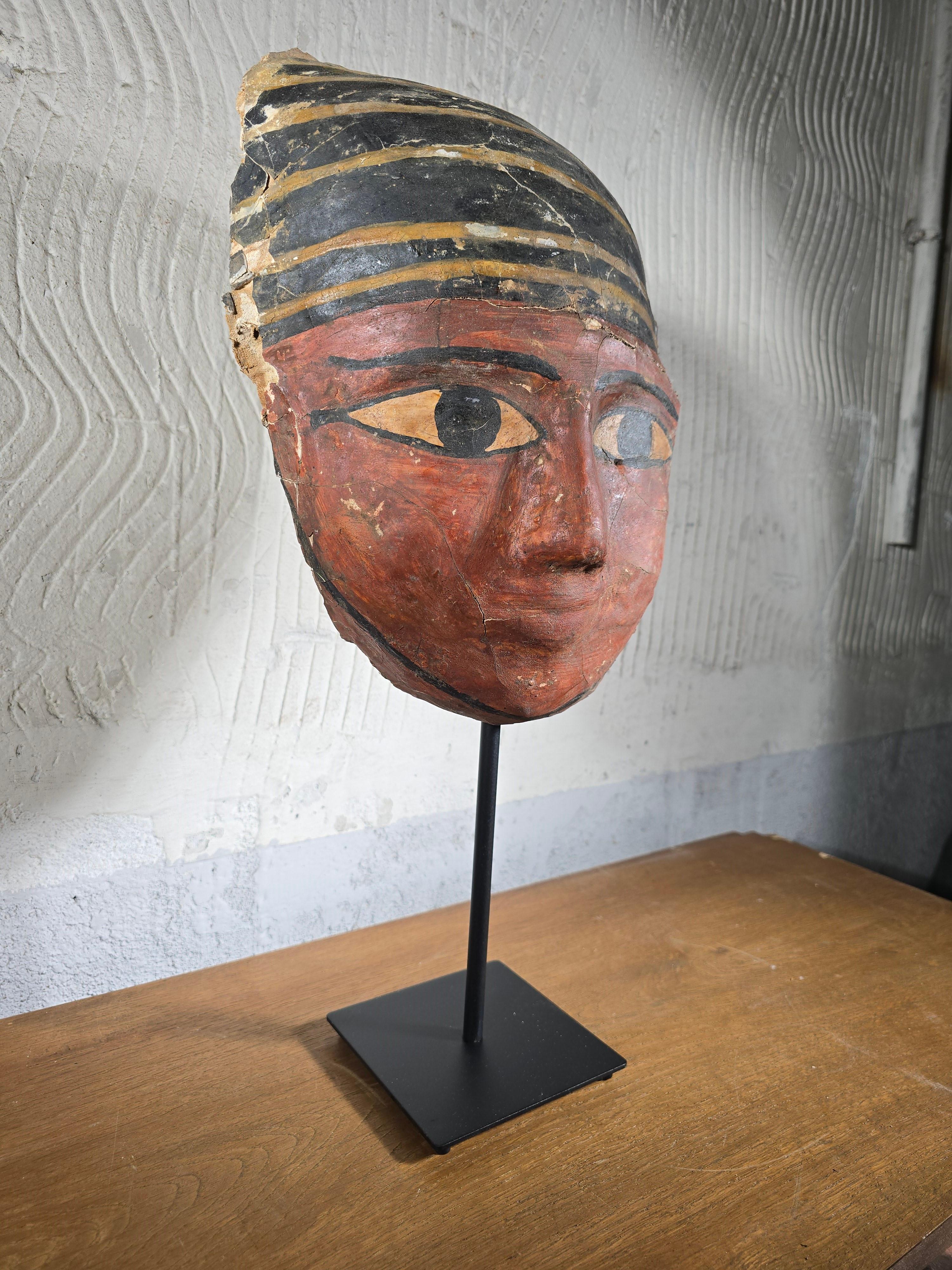 An important Egyptian sarcophagus mask from the Ptolemaic Period (711–332 B.C.), crafted with remarkable artistry and historical significance.

Material: Made from stuccoed linen textiles (cartonnage) with vivid colored pigments.
Condition: Shows