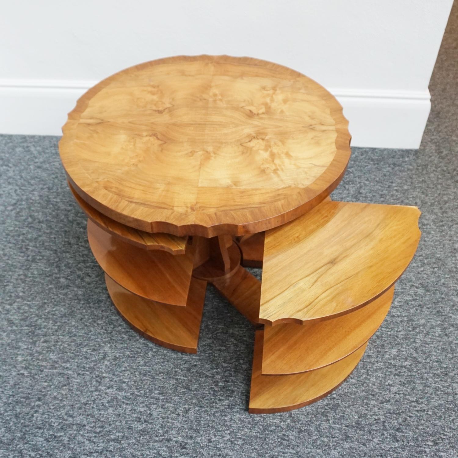 An Art Deco nest of tables by Harry & Lou Epstein. Burr walnut veneered with figured walnut banding. Curved edges to table top with four integral side tables. Cross-footed figured walnut base. 

Dimensions: D 76cm H 56cm Nest H 49cm Nest W 51cm D