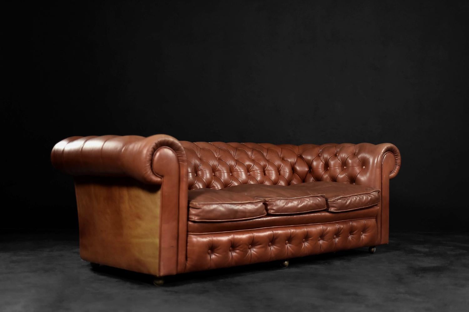 This original three-seater leather Chesterfield sofa was made by Artistic Upholestery Limited in England during the 1950s. It is an example of the classic English style from the 19th century. The item has original sign. It is one of the most