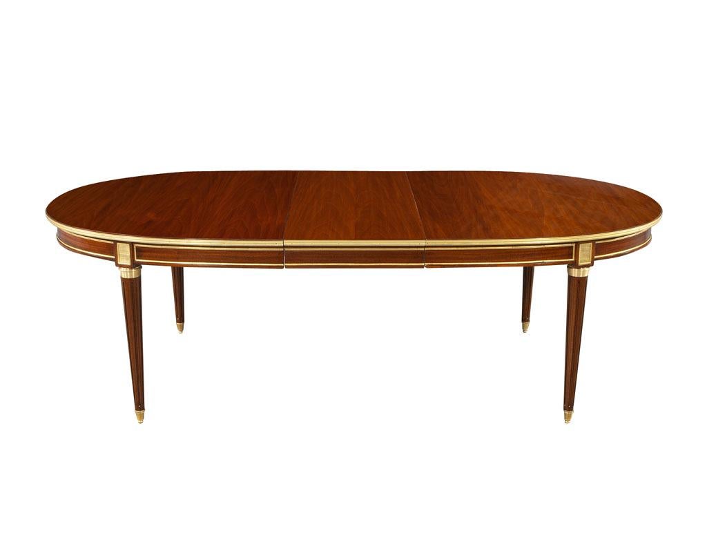 Original French 1940’s Maison Jansen dining table Polished Mahogany with brass detailing. France, circa 1940’s, all original. Featuring French polished mahogany colored finish with all original brass ornaments. Table features 2 leaves with hideaway