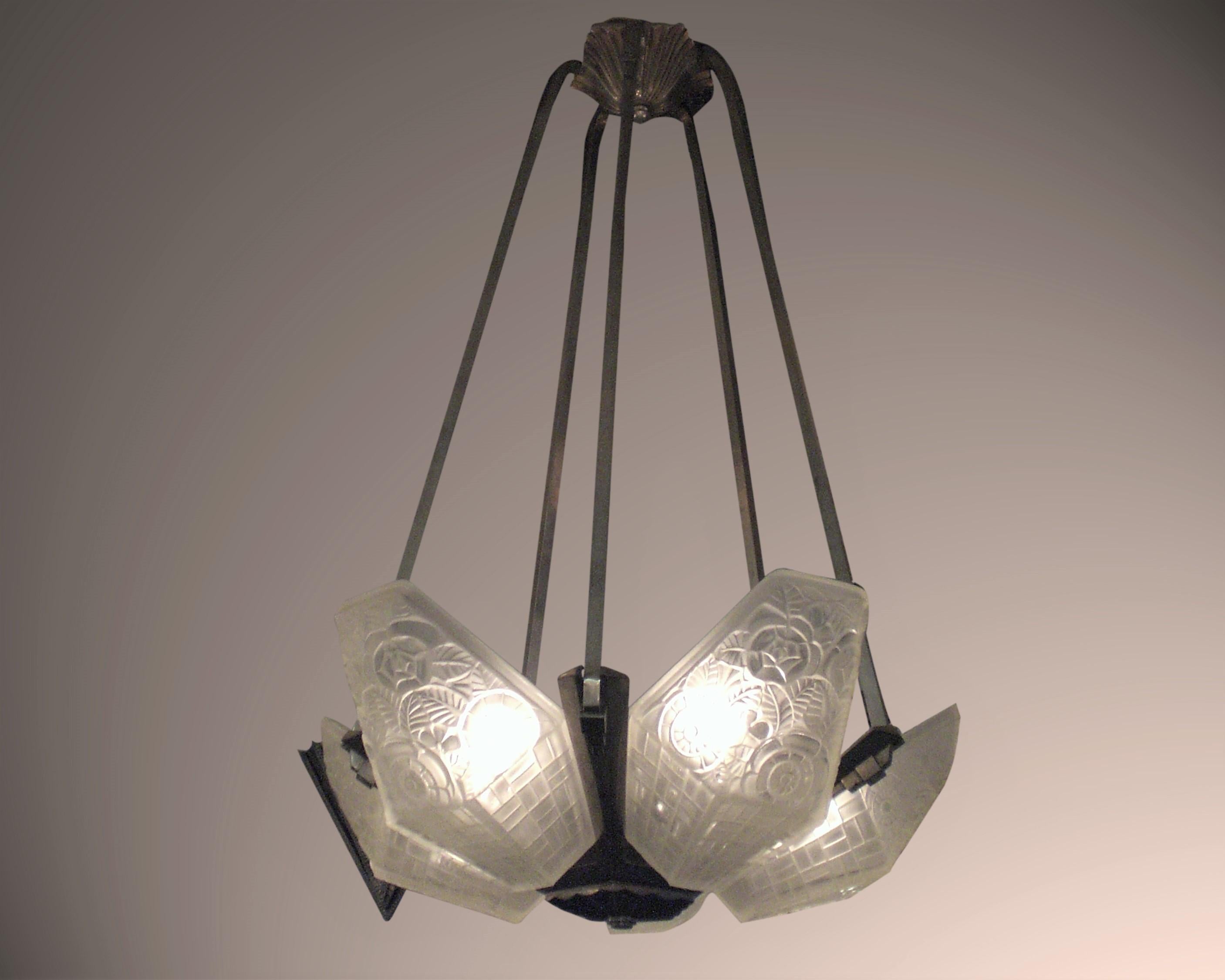An original French Art Deco period frosted art glass chandelier. Five angular panels with geometric motif of basket weave and stylized floral pattern, mounted in original nickeled bronze armature. Attributed to Hugue.
Original nickeled finish with