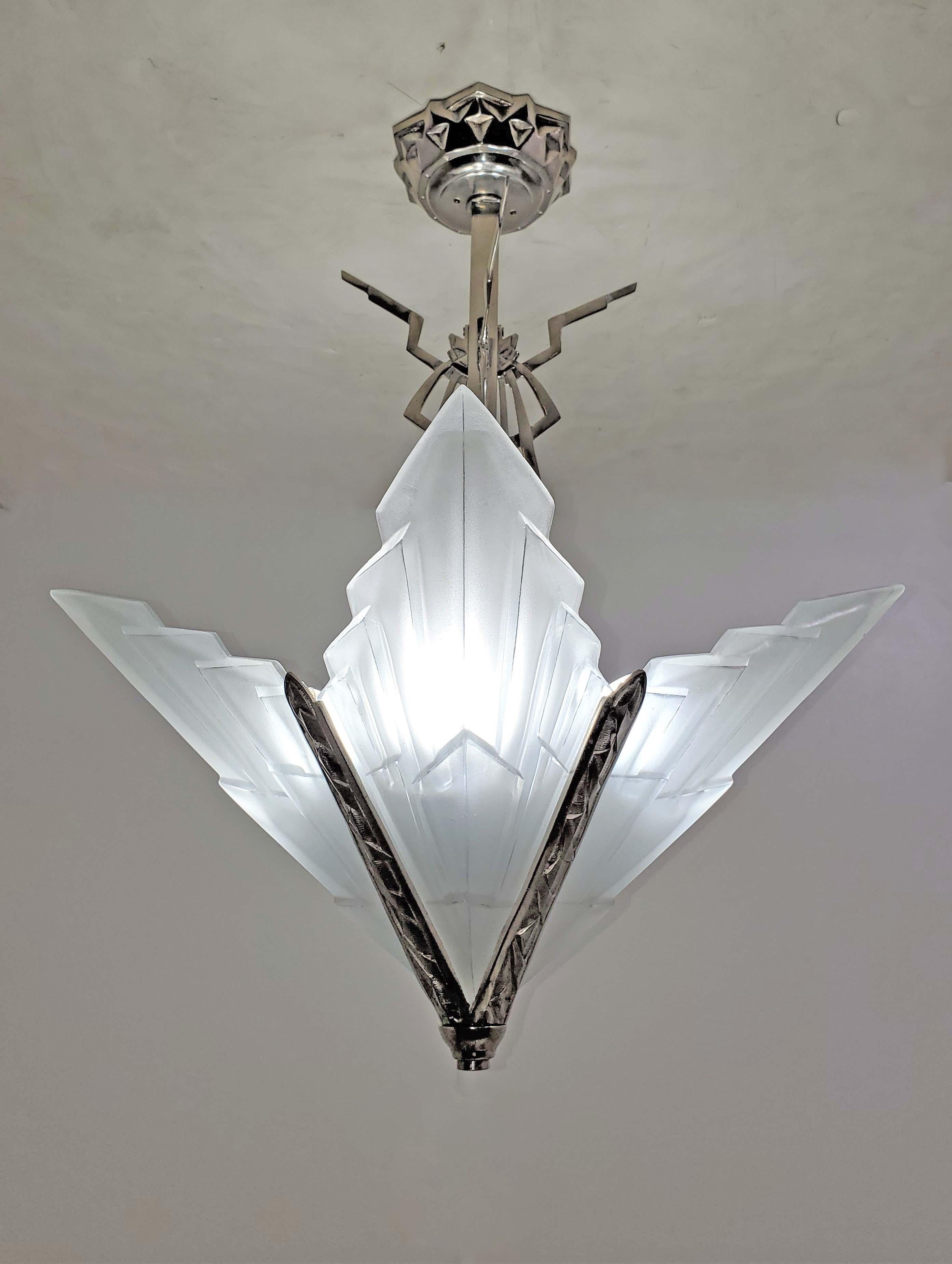 French Art Deco geometric motif chandelier signed Degue featuring four wing shaped frosted and molded art glass panels with chevron design, jagged ends and polished details.  
The architectural panels jut upward and outward in an unusual star