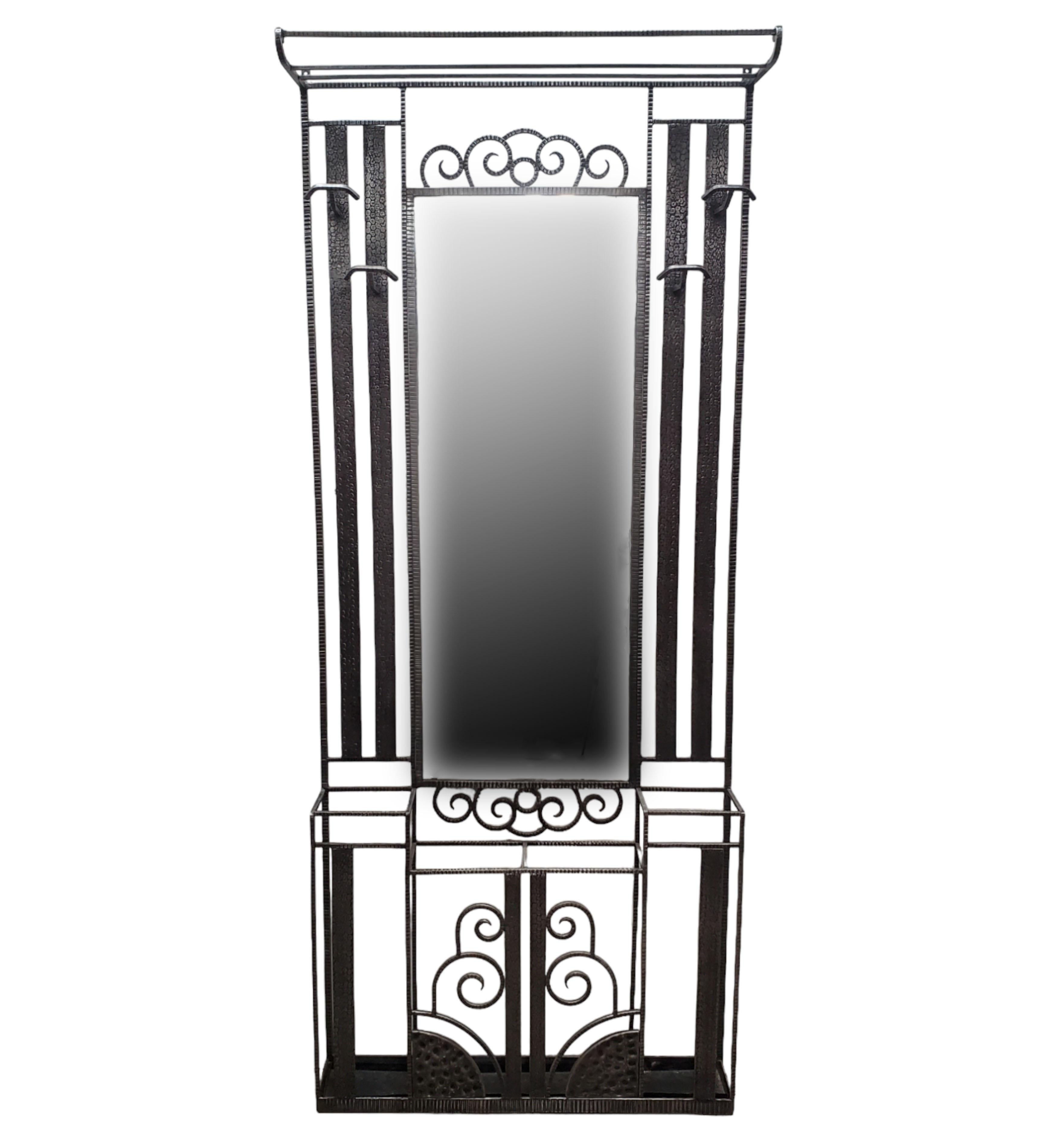 An original French Art Deco hand-hammered iron hall tree circa 1920, complete with hat, coat and umbrella accommodations. The architectural and linear design depicts highly stylized geometric patterns of scrolling waterfall designs and is