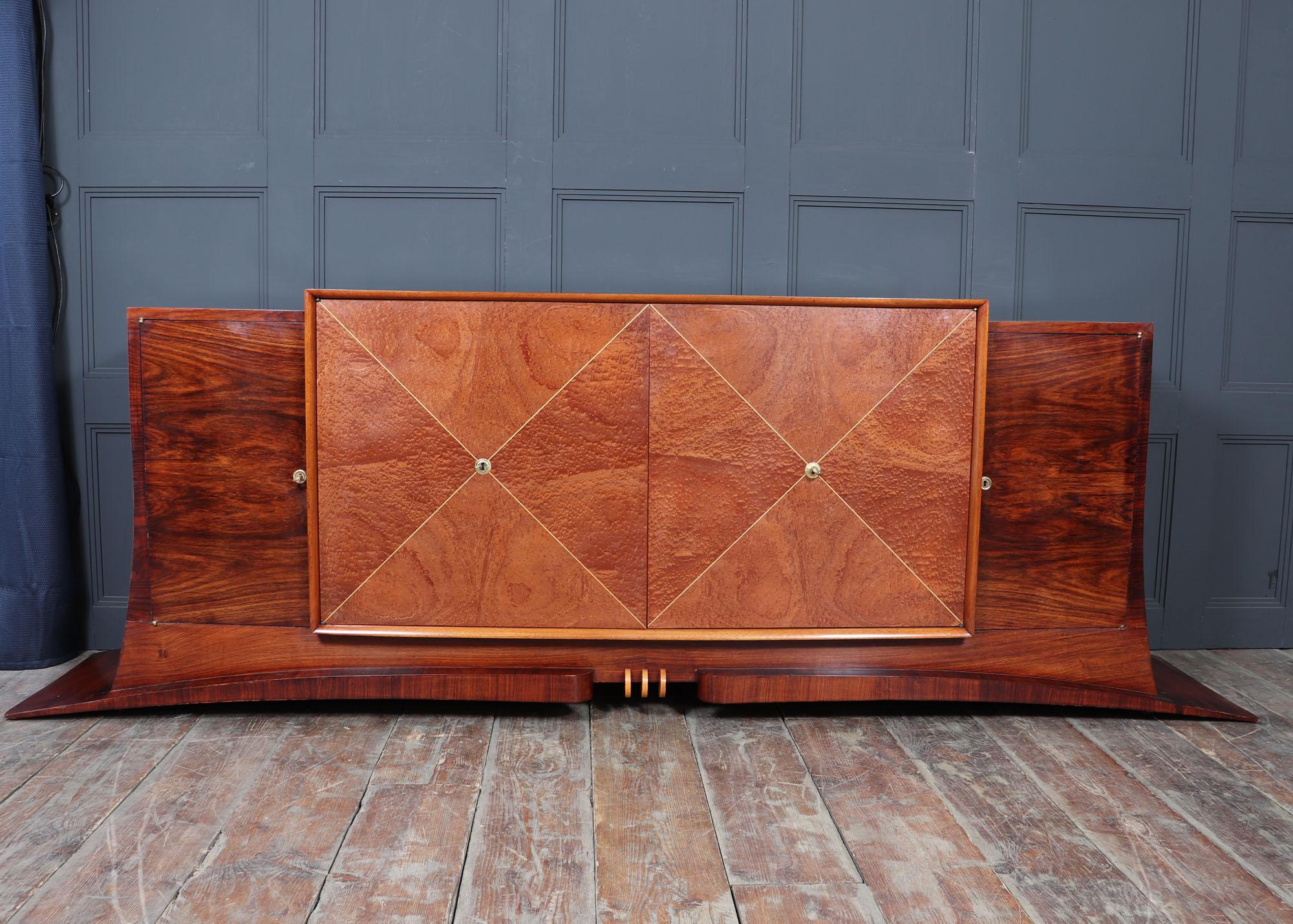 An exceptional original French Art Deco sideboard, crafted circa 1930, showcasing the geometric elegance and material opulence of the period. The dramatically curved body is clad in highly figured rosewood, offset by a central pommele sapelle