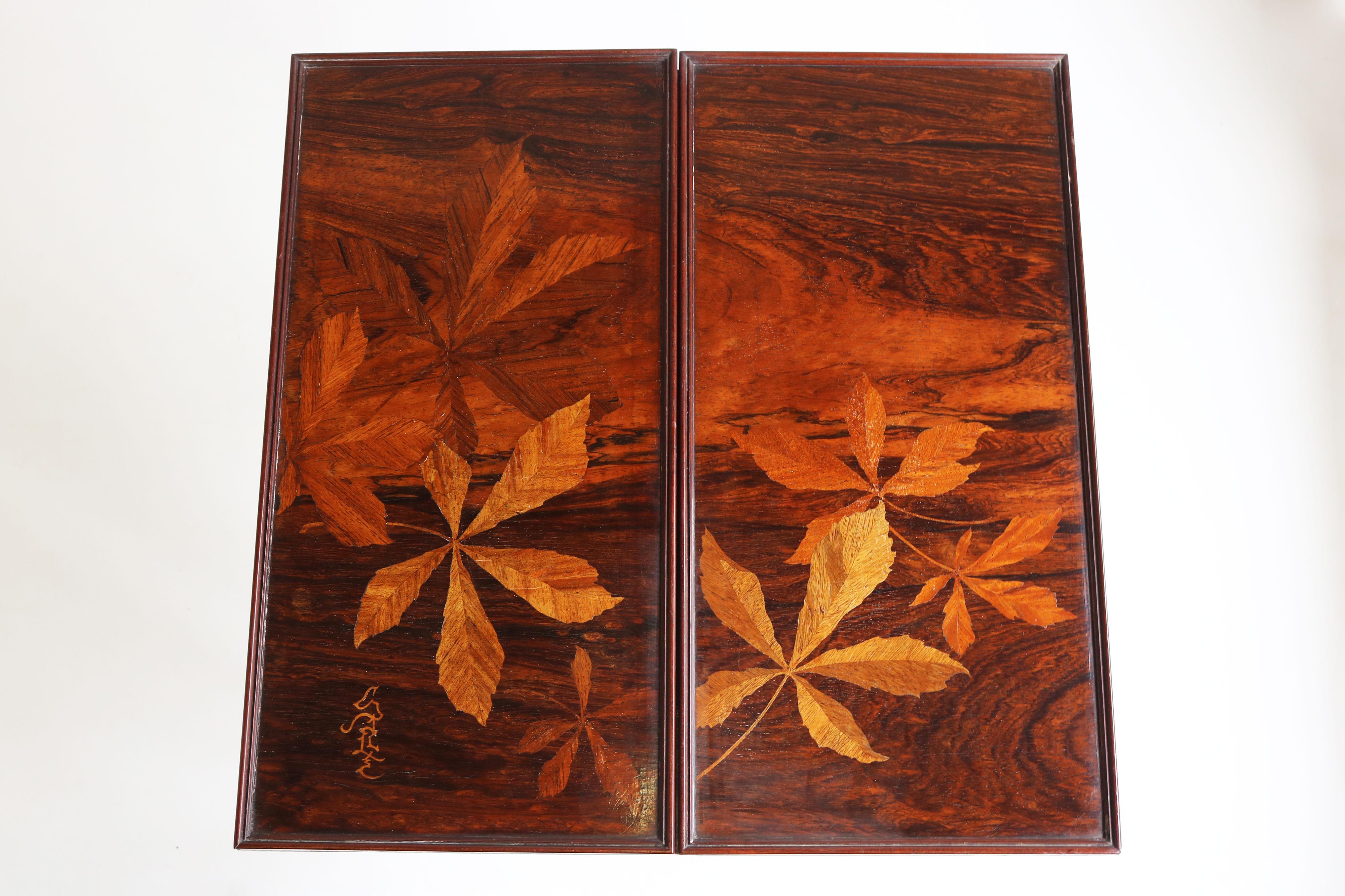Exquisite & most rare! This marvelous games table by Emile Galle. The top is richly decorated with a masterfully inlay of various woods. Depicting multiple chestnut leaves in different colors. 
The top is signed Galle in inlaid wood made in