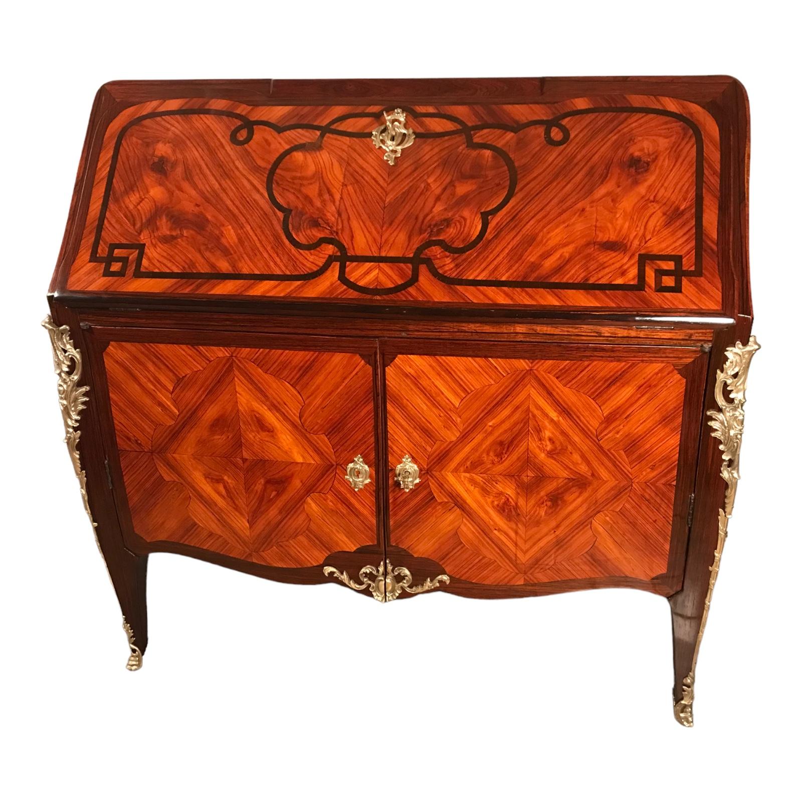 This French Louis XV secretary desk dates back to around 1760 and comes from Paris. This exquisite piece stands out for its beautiful kingwood veneer and marquetry on an oak carcass. The secretaire with a serpentine shaped front stands on four