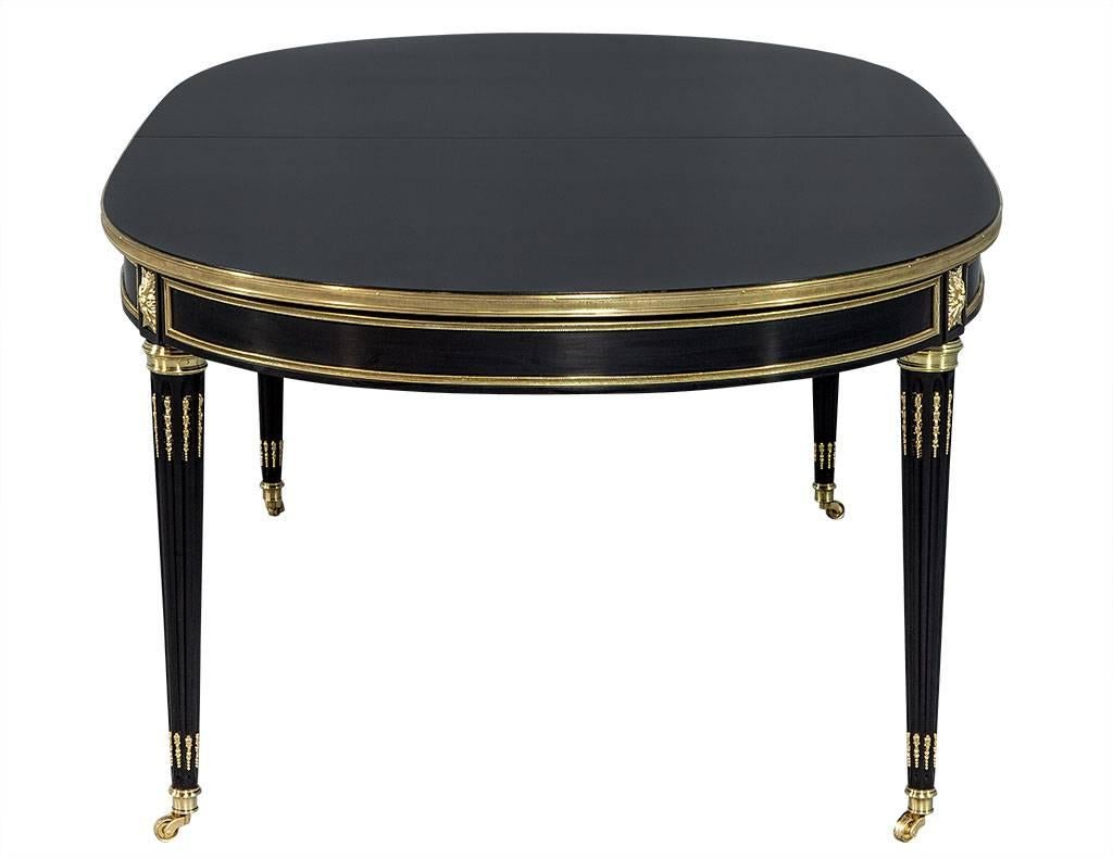 This original French Louis XVI style dining table dates back to the 1960s by designer Maison Jansen. The table has two centre leaves for additional length. The table has been hand polished in black lacquer with all original polished bronze mounts