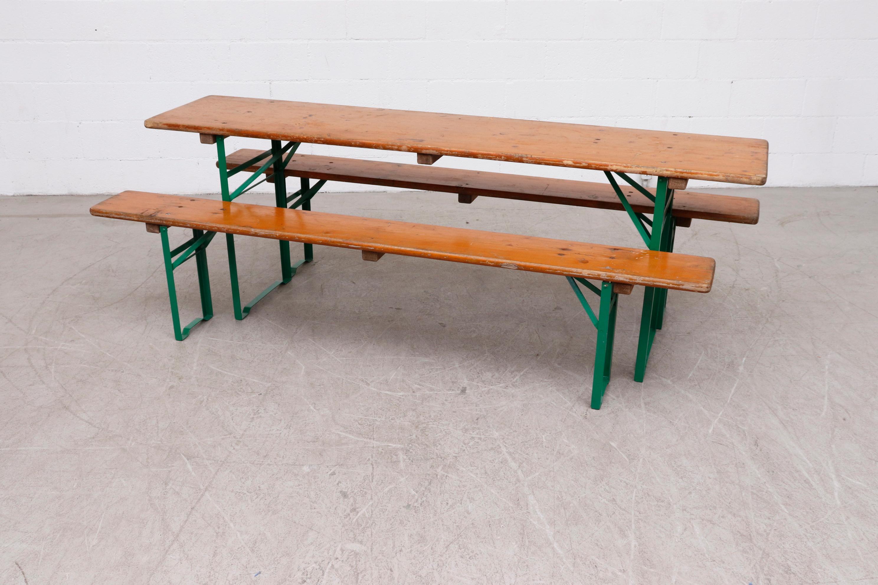 Original German beer garden wood topped folding table and bench sets. Sold as a set of 2 benches and 1 table. Metal is in original condition with visible patina. Wood in original used condition as well. Sets vary in color and wear. Benches measure