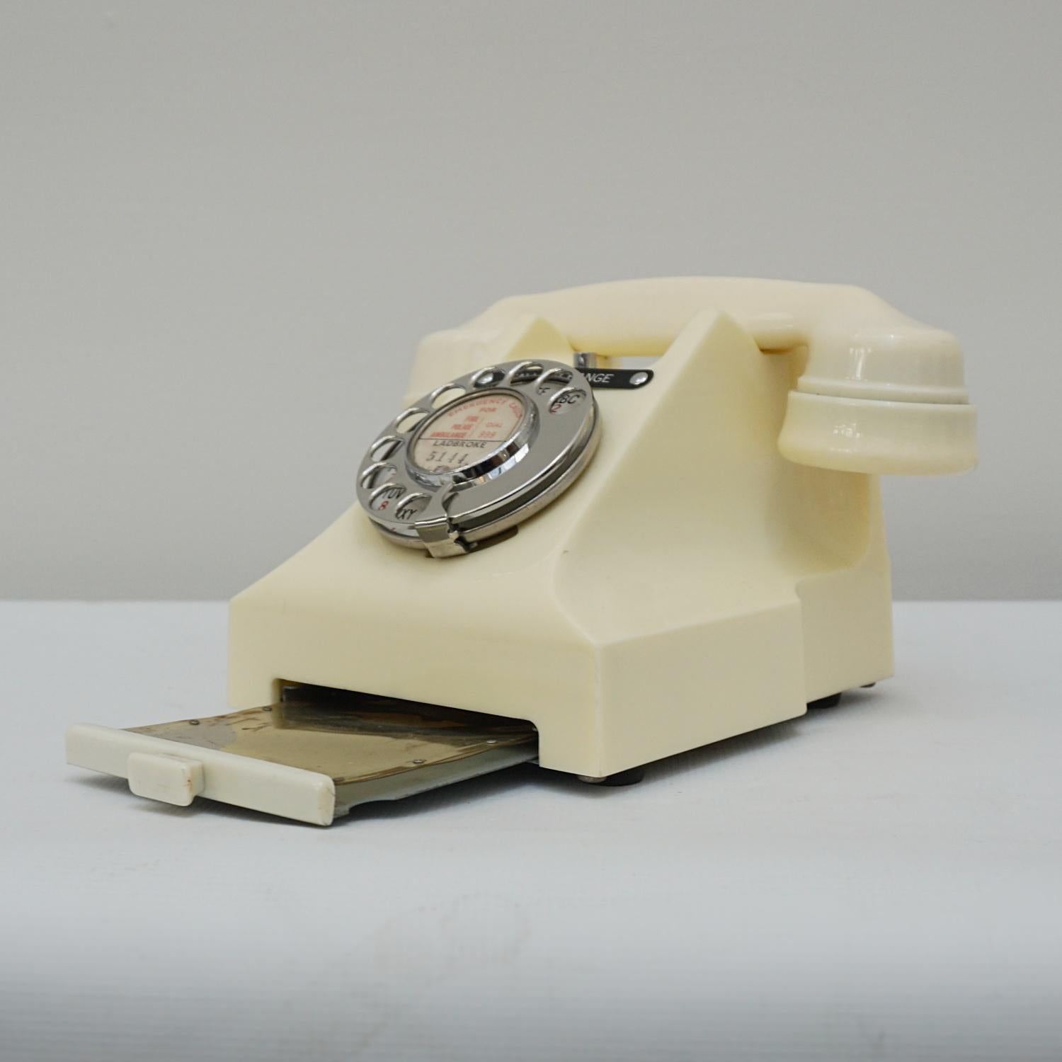 An original GPO model 332L Telephone. White bakelite with integral drawer and braided handset cord. Registered number to face and call exchange button. 

Dimensions: H 15cm, W 20cm, D 16cm

Origin: English

Date: 1956

Item No:
