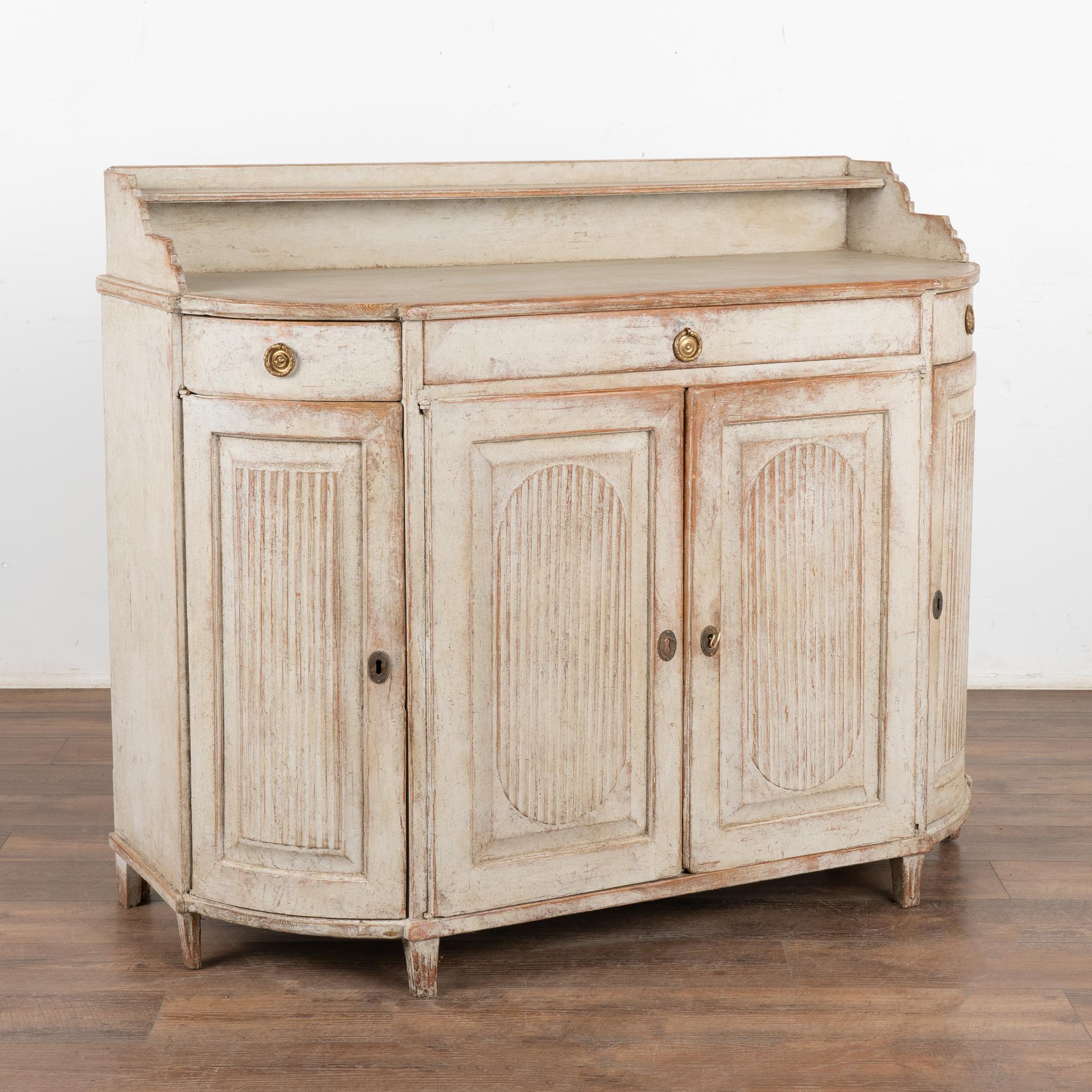 Swedish Gustavian original gray painted pine sideboard with attractive curved sides and traditional fluted panel details.
The curved end cabinet doors and drawers make this cabinet a special find.
The gray painted finish has been lightly distressed