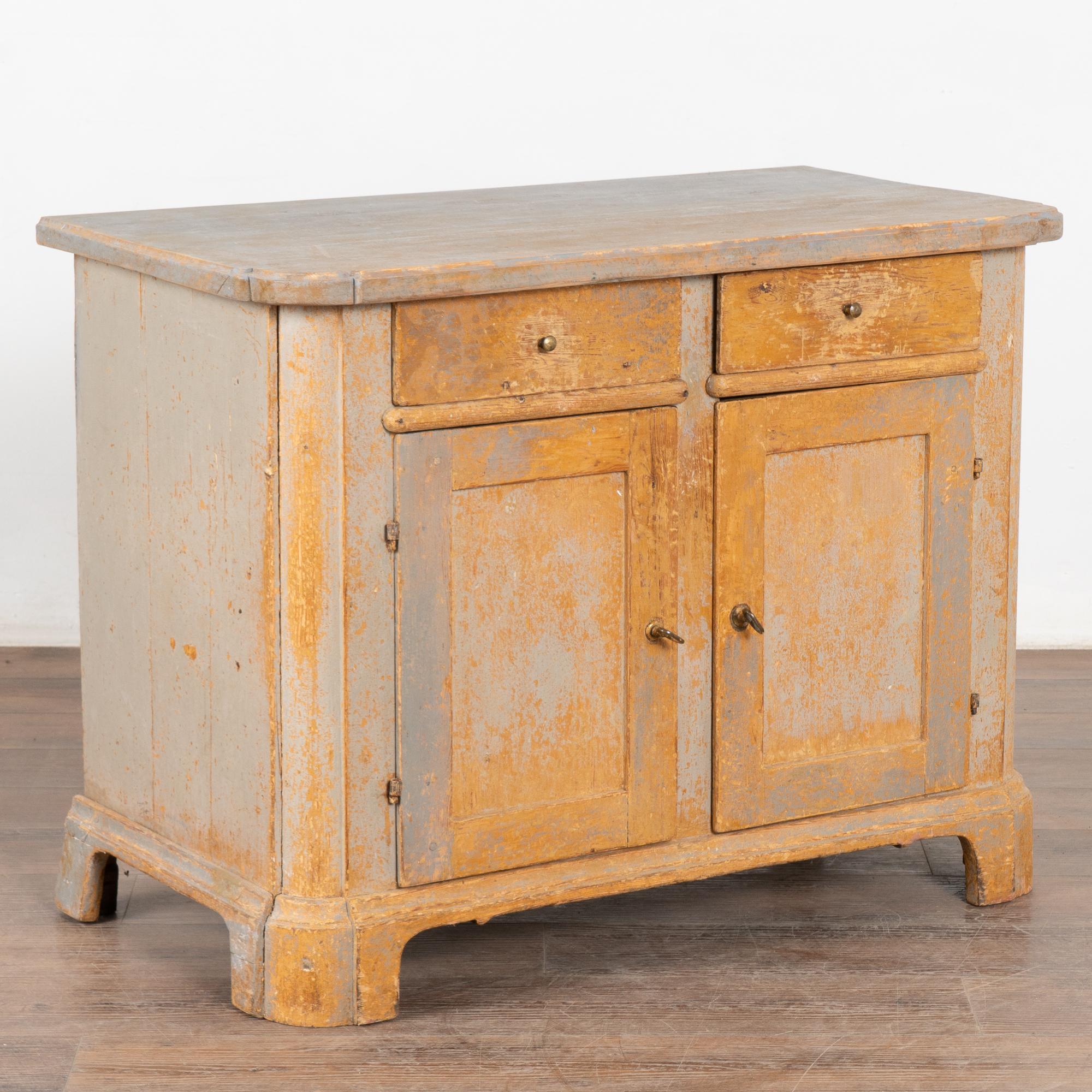 Pine sideboard with generations of use revealed in the wear and distress to the original painted finish. Shades of both blue and gray are seen, with an overall impression of gray which has been greatly distressed revealing the natural pine wood