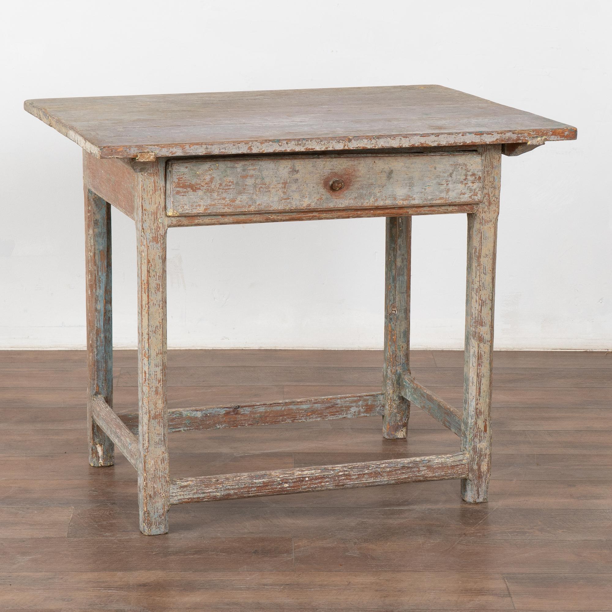 Mesa auxiliar de pino pintado original del país sueco con un solo cajón. 
La pintura gris antigua original se ha desgastado hasta la cálida pátina de pino que hay debajo. Suaves matices de lavanda, con toques de azul, verde, blanco y amarillo que