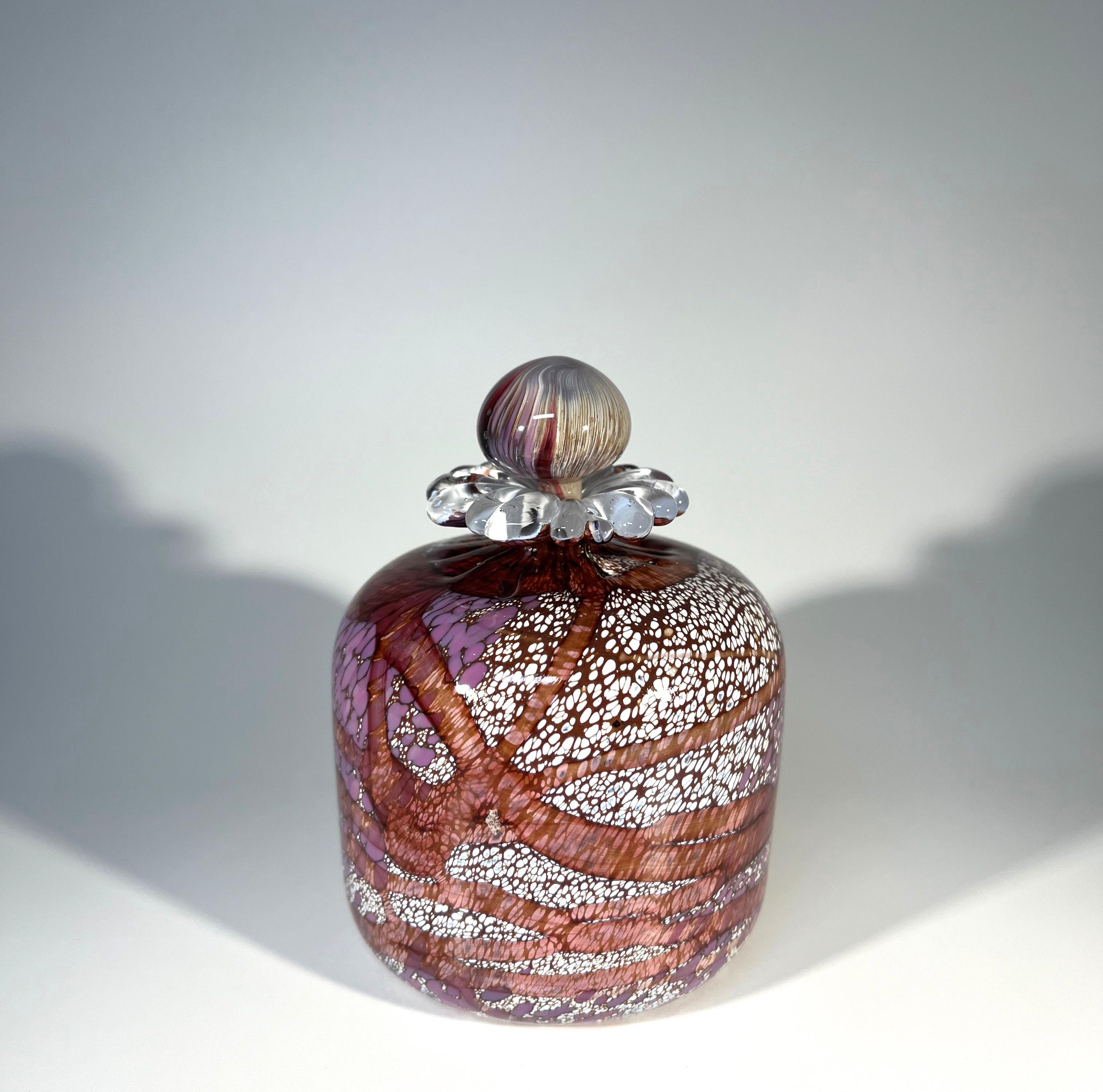Desirable perfume bottle, hand blown by Guernsey Island Glass Studios in the Channel Islands
Created using a glass palette of fragrant lilac, plum and white blossom with daisy petal collar
The stopper is a swirl of complimenting hues
Pontil on base