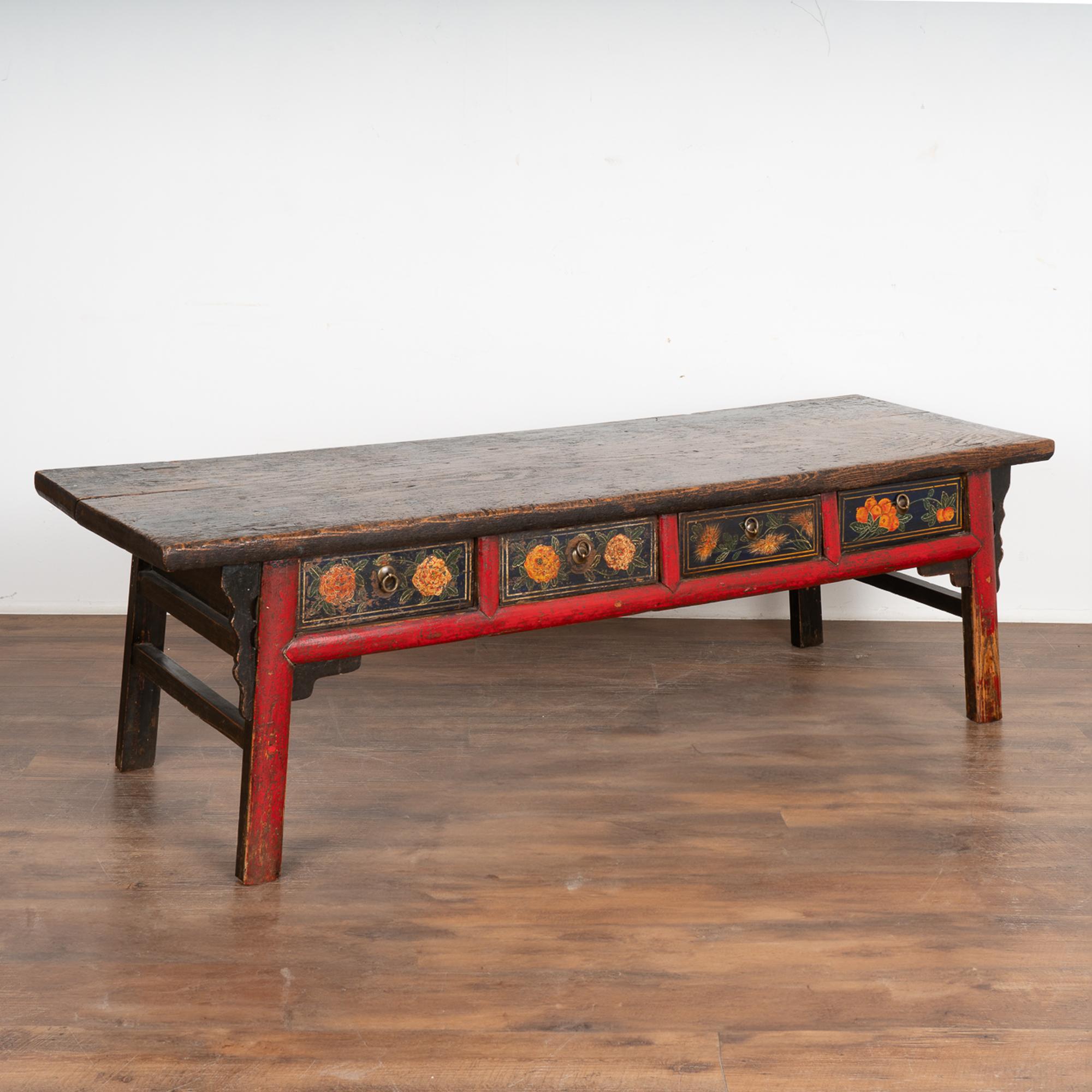 This striking coffee table is an exceptional find. Note the original hand painted flowers and red trim highlighting the legs and back.
Enlarge photos of the top to appreciate the thick wood, which was once painted black but is now worn and
