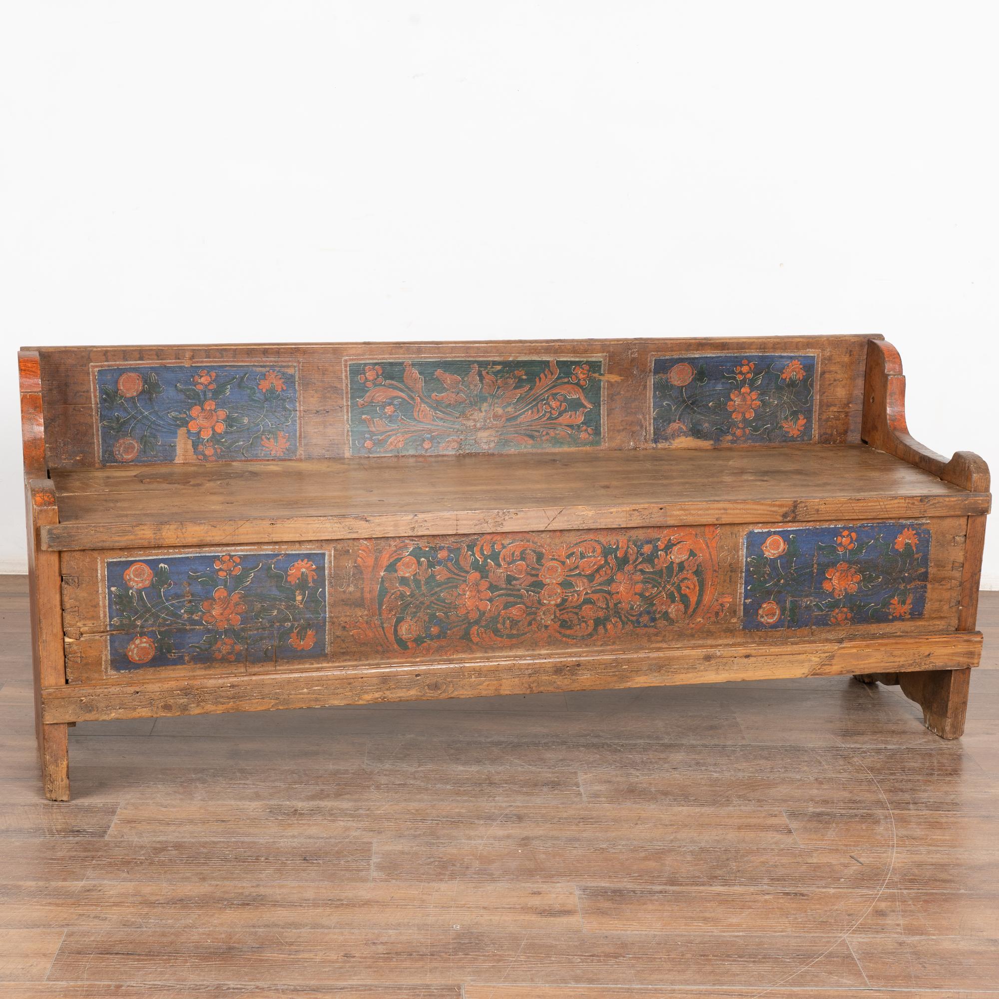 Antique hand painted pine bench embellished with traditional Eastern European folk art painting with blue background and red flowers.
Bench seat opens to reveal two painted trees and interior storage. Base can open as it was originally used as a