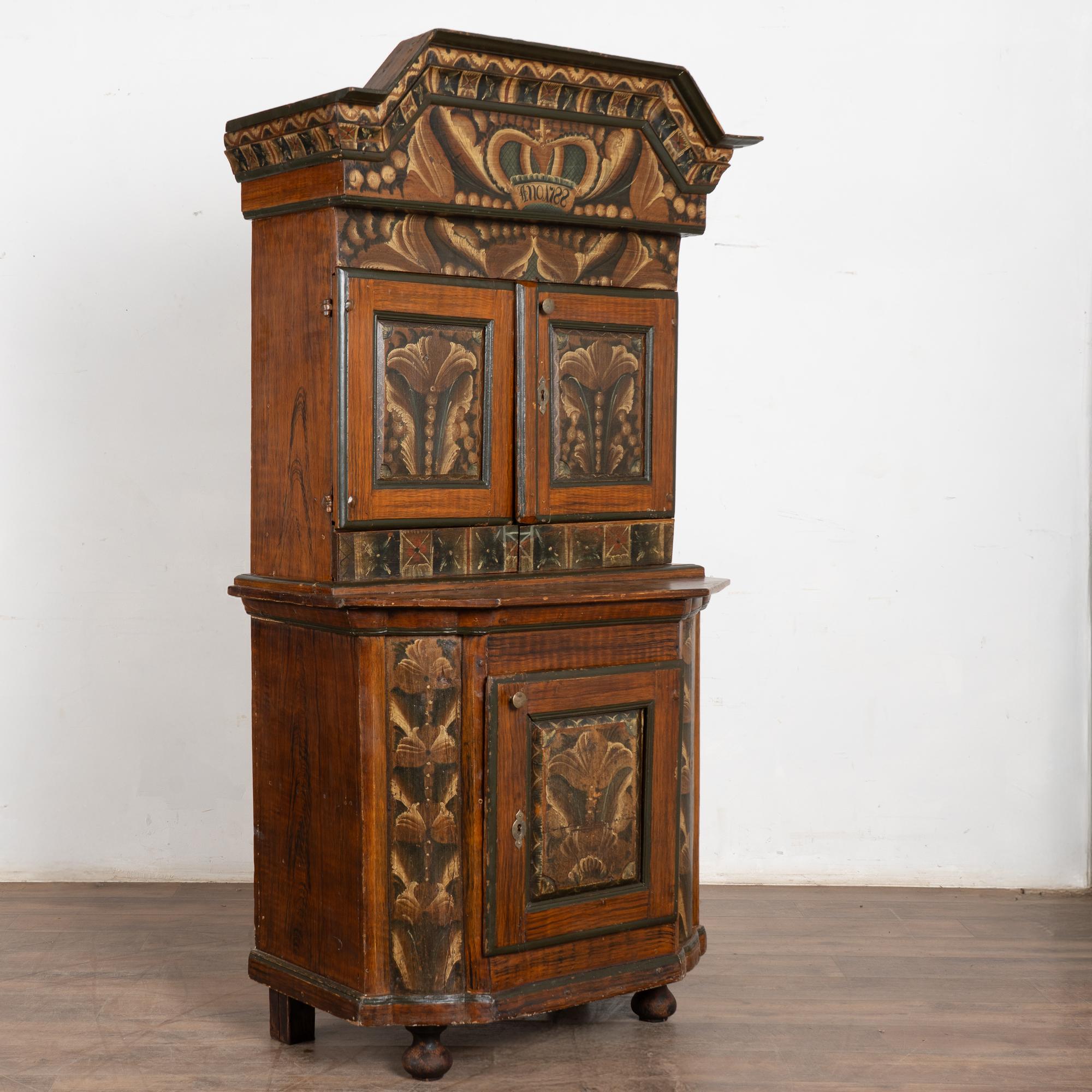 A wonderful example of Swedish country craftsmanship and folk art painting from the Dalarna region of Sweden.
This cupboard is exquisitely painted in earth tones and decorative patterns throughout. Of special note is the large step cut crown molding