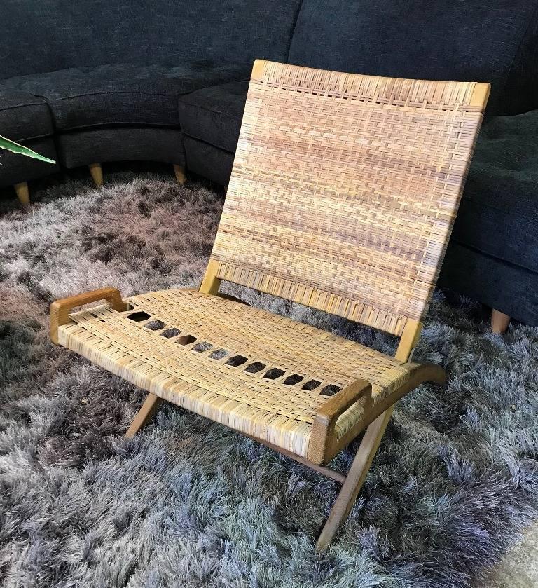 Conception et esthétique emblématiques. Cette exquise chaise pliante a été conçue par le célèbre designer danois Hans Wegner. Elle est dans sa finition d'origine et son siège et son dossier en canne. La chaise porte la marque et le cachet