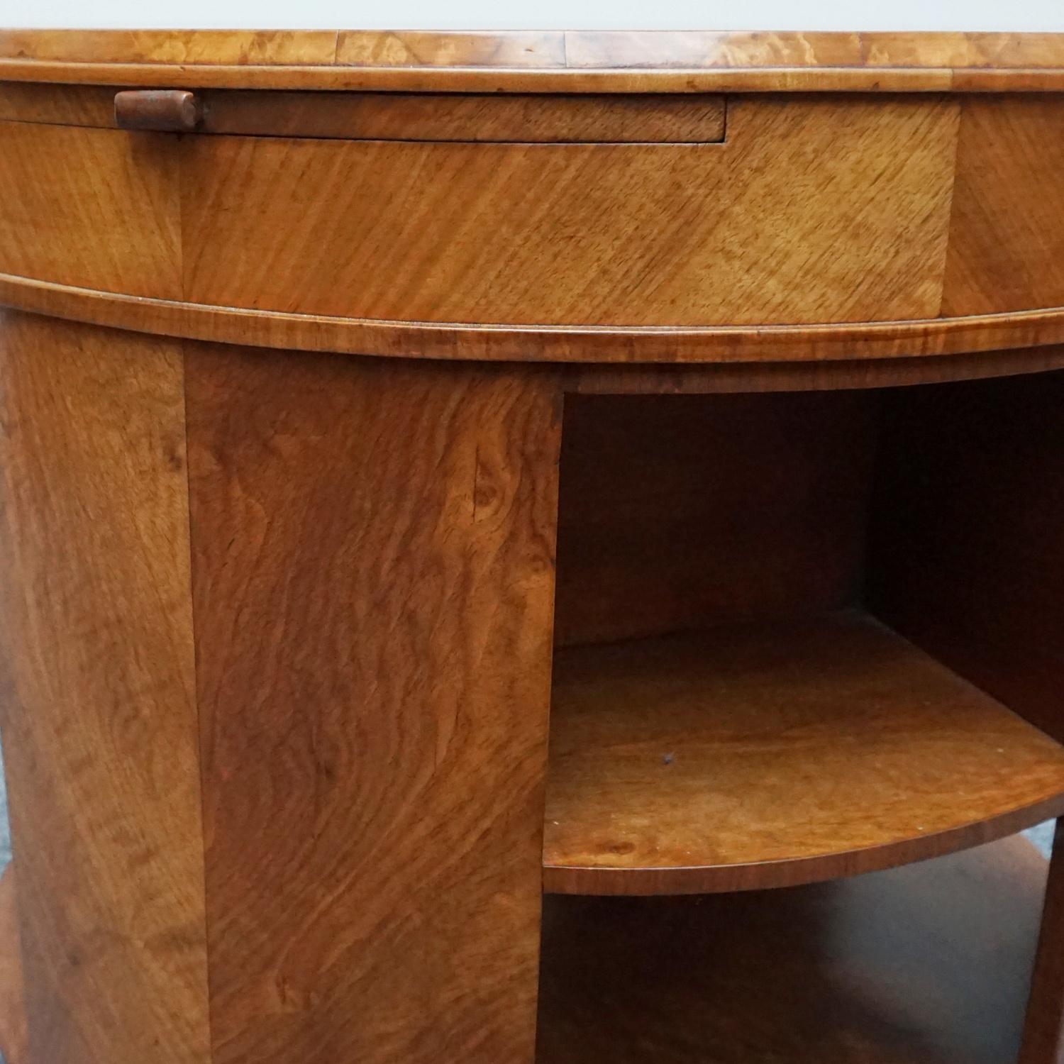 An Art Deco library table by Heal's of London. Burr and figured walnut veneered with four graduating Karelian birch veneered sliding trays. Lower section opens through with four upper shelves. On original castors. 

Dimensions: H 63cm D