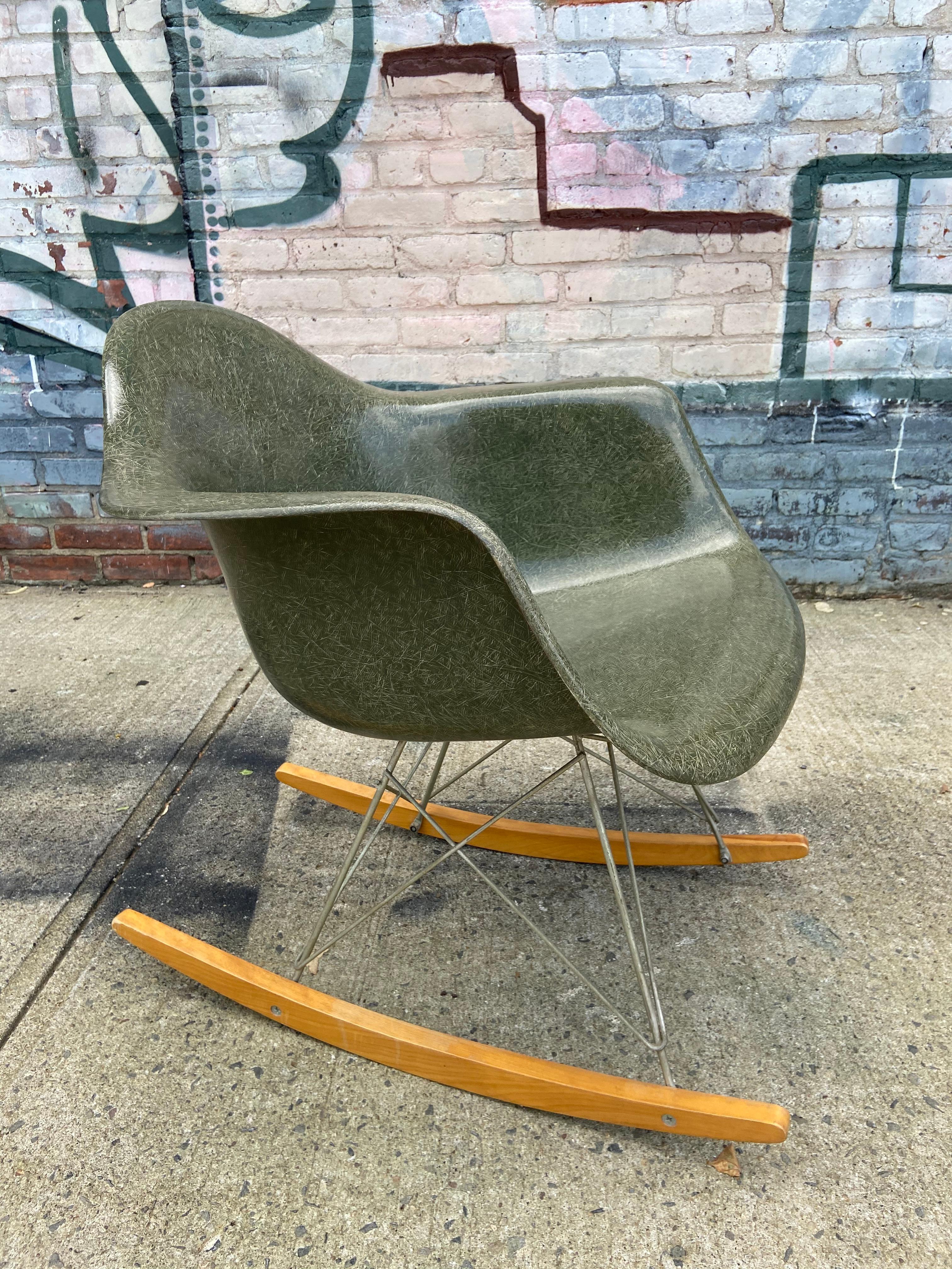A wonderful example of the modernist design classic. This Eames rocking chair with original base and runners. It is the rare olive green color which is very hard to come by. Fiberglass shell with gorgeous texture and fiberglass grains. Zinc plated