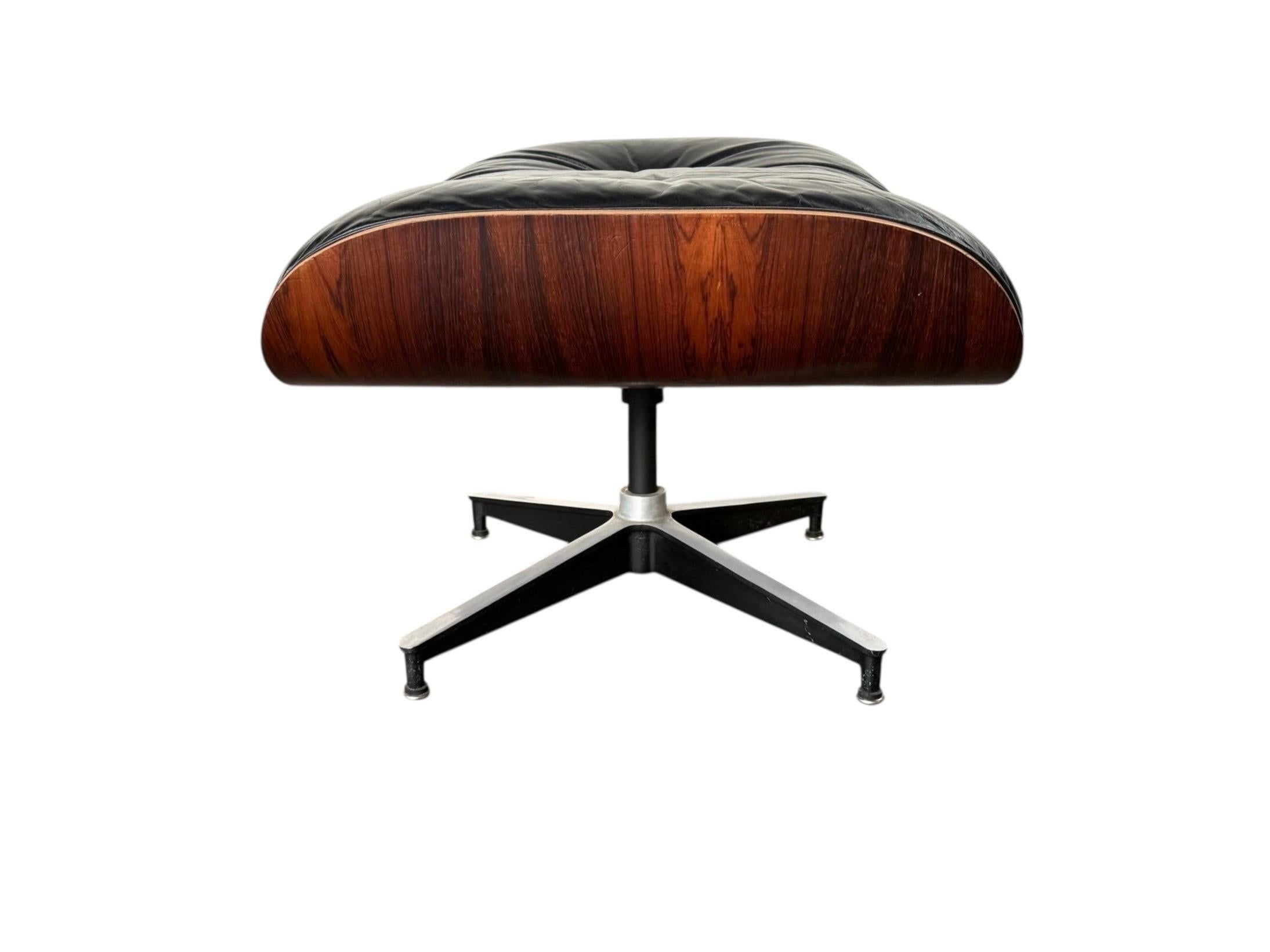 Pouf originale Herman Miller Eames (modello 671) da utilizzare con la poltrona Eames. Scocca in palissandro e cuscino in pelle nera su una base in alluminio fuso. L'imbottitura in schiuma è ancora molto confortevole. Tutti i pulsanti, le viti,