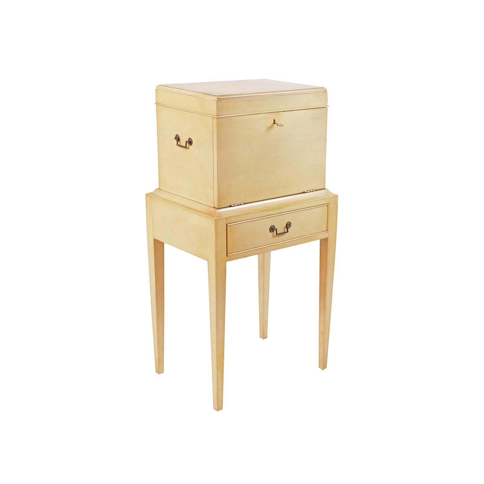 Mid-20th century Hollywood Regency fitted flatware chest or canteen on stand in the original cream paint. The top unlocks and opens to a fitted and clothed upper shelf and the front folds down to expose three more fitted and clothed drawers. The