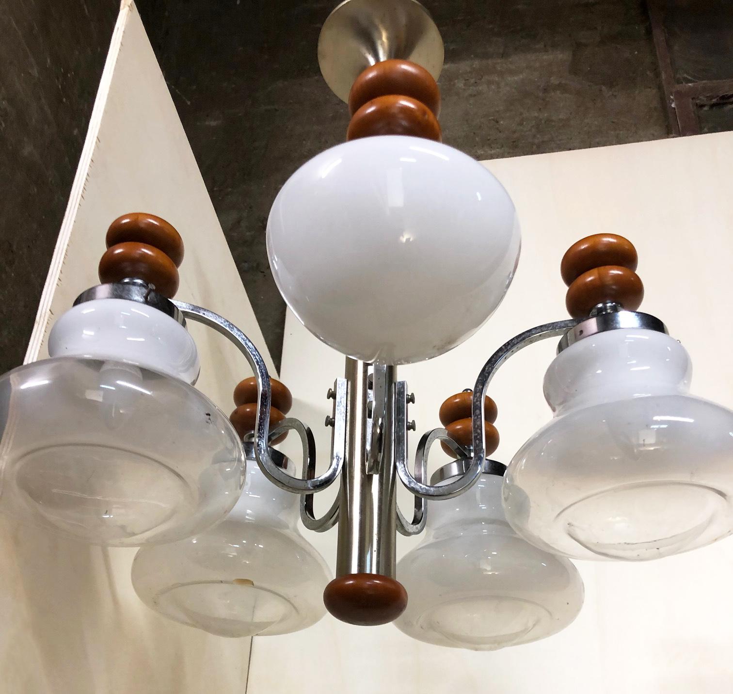 Original Italian five-light chandelier, from 1970, chrome, wood and glass.
One of the five glass lampshades is of a different shape and completely white
The fixture requires five European E14 candelabra bulb
In working condition
We recommend buyer