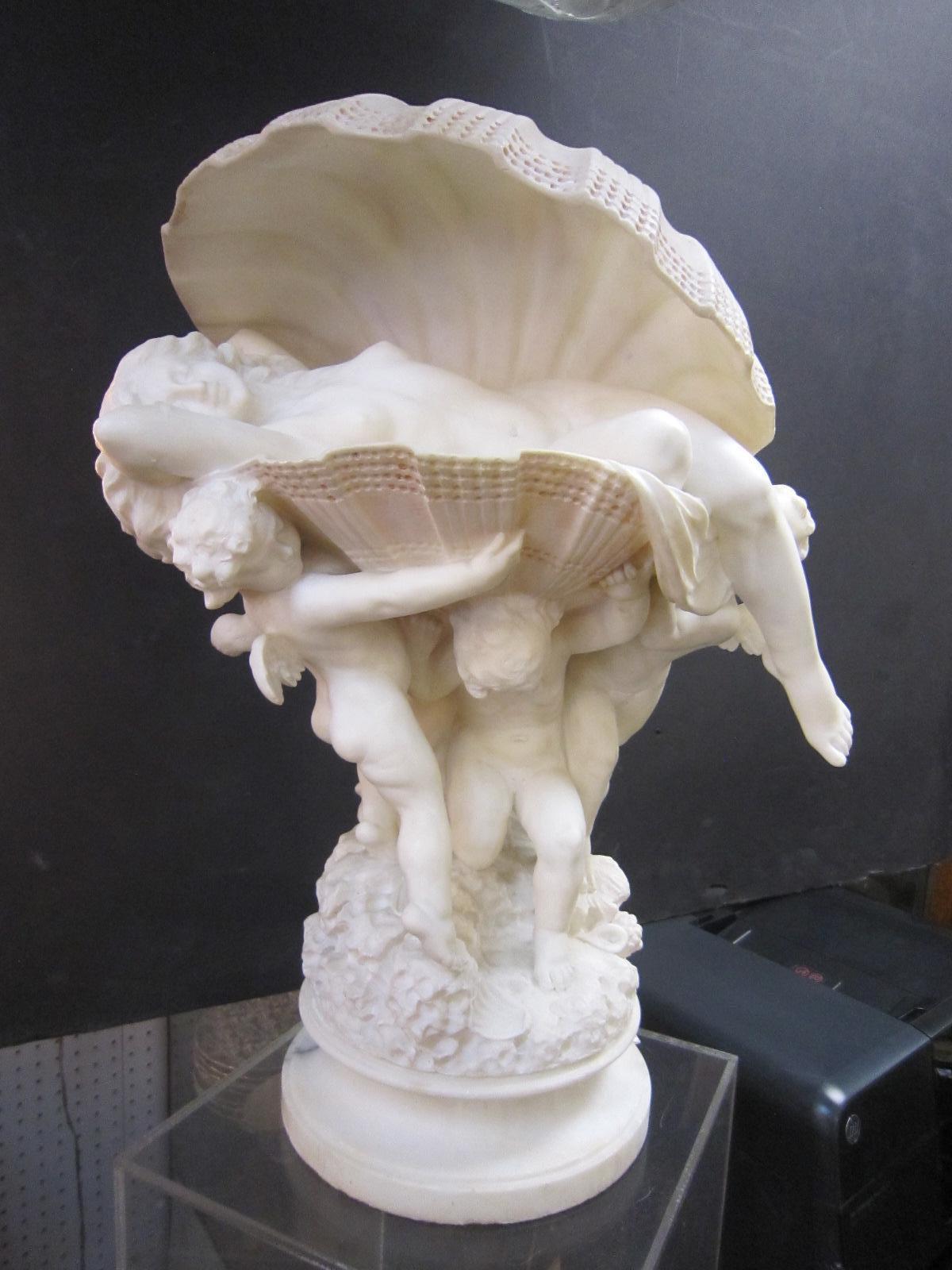 Sculpture en albâtre blanc, sculptée à la main, représentant une femme nue allongée dans une coquille de palourde, avec trois putti ailés la portant.
dans les eaux chargées de coquillages.
Signé au verso par l'artiste italien du 19e-20e siècle, le