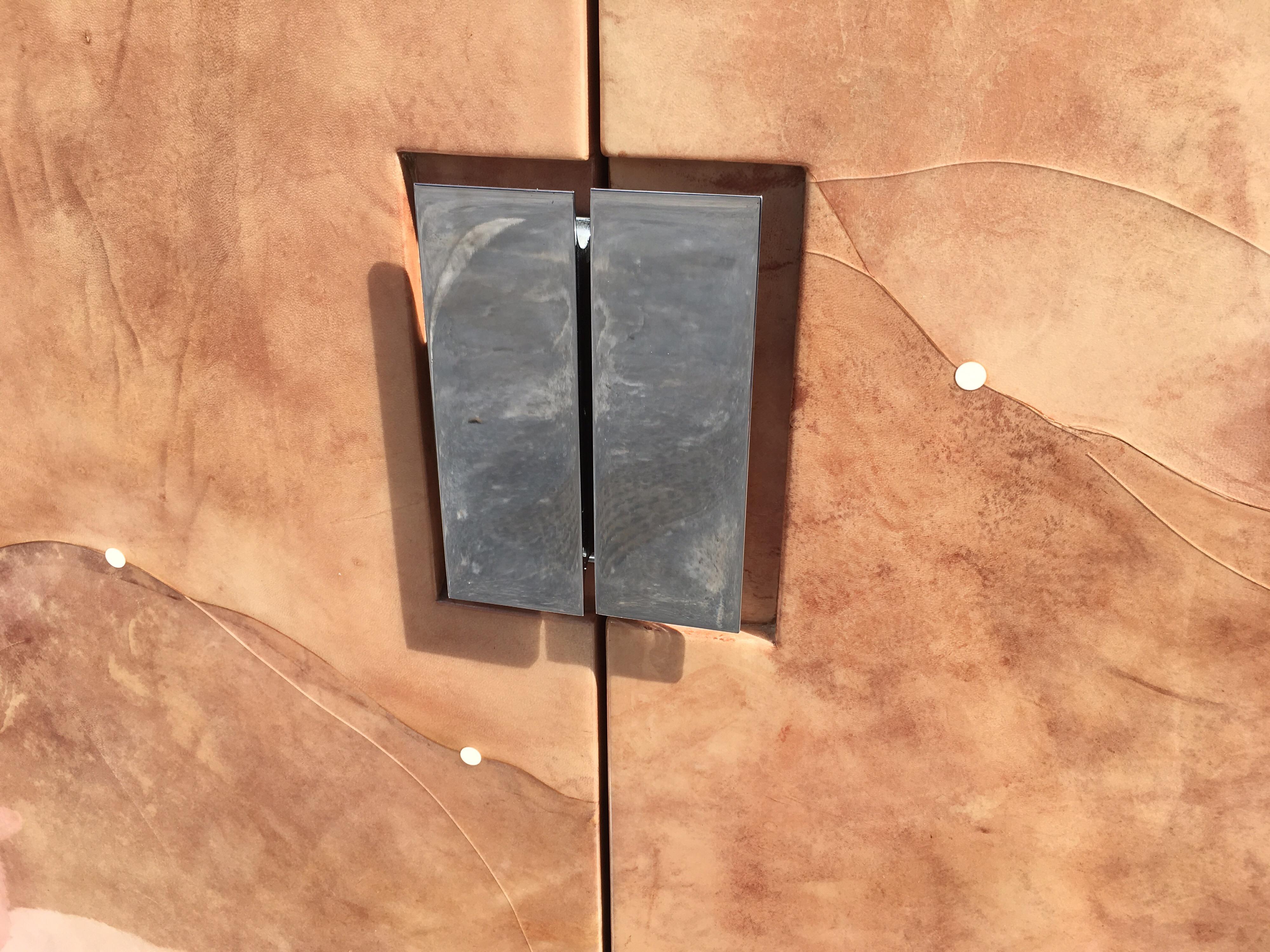 Cabinet covered in goatskin with clear finish. Two doors with stainless steel pulls, cabinet has black interior.