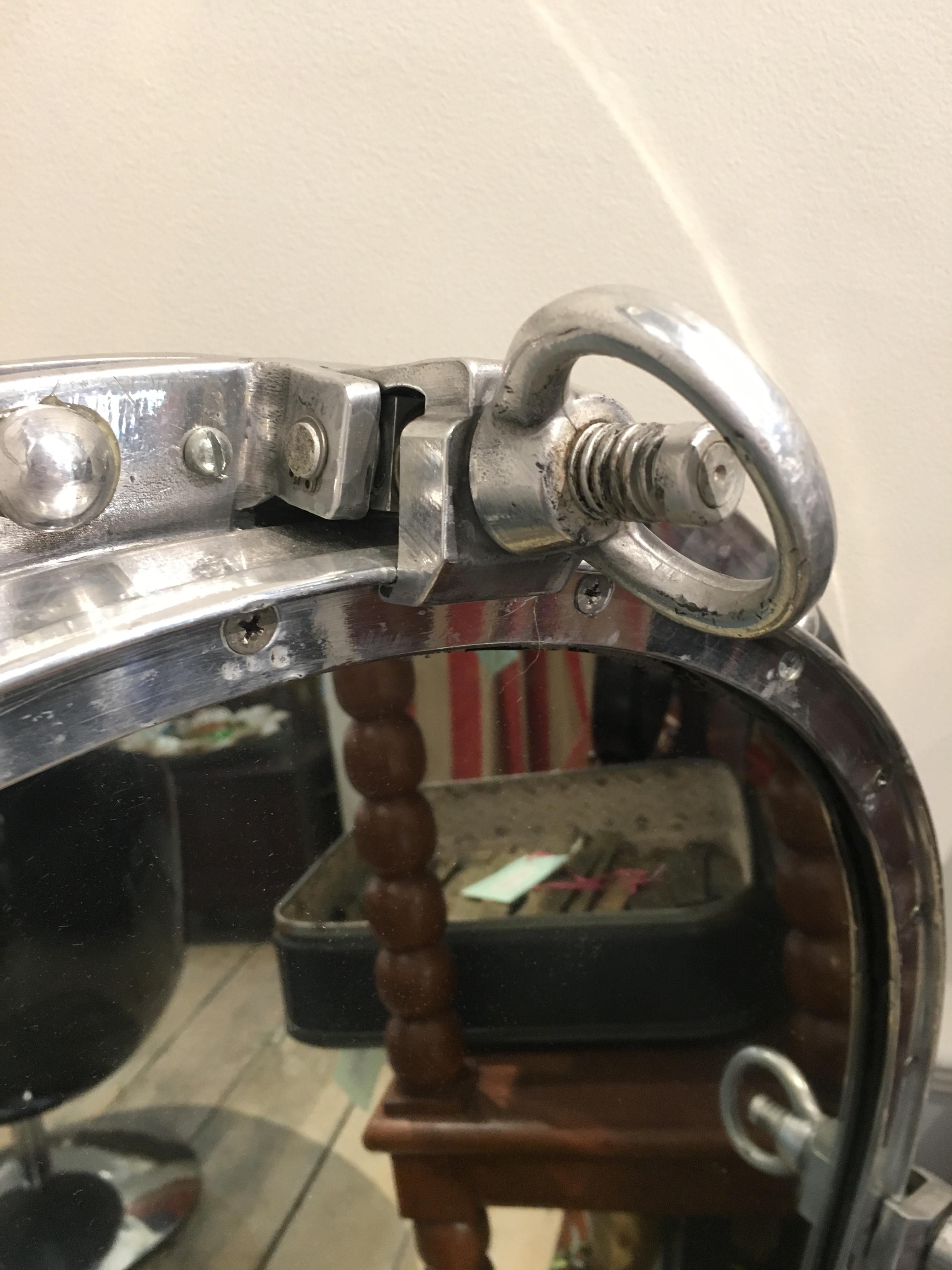 An unusual large size, oval ship's porthole window converted to a mirror. Chrome window with working keys--the keys turn and the window opens (put a safe or shelves behind?). From a decommissioned ship form the 1970s. The rivets have been put back