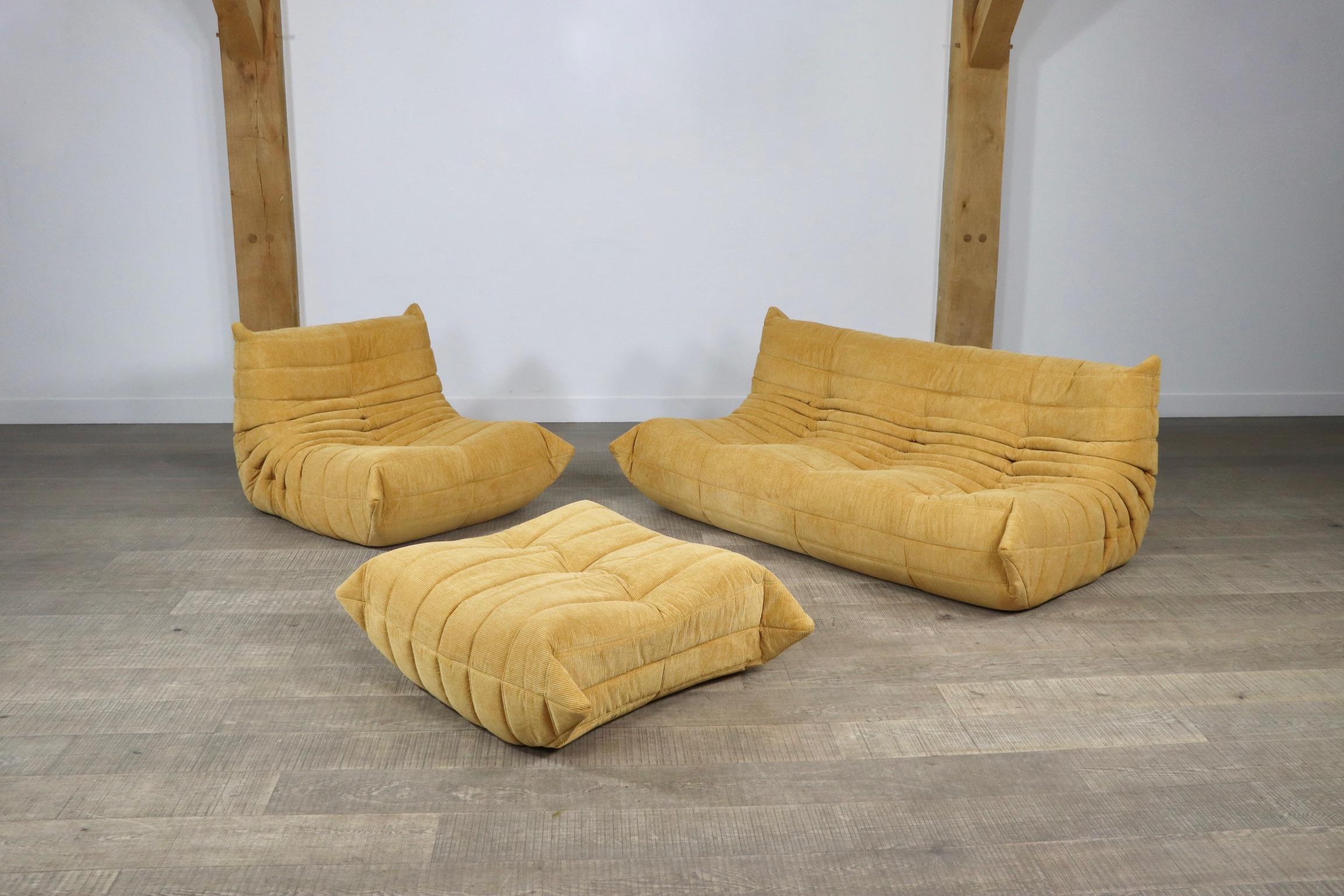 Beautiful mustard corduroy Togo seating group by Michel Ducaroy for Ligne Roset, 1970s. The entire seating group has the original Ligne Roset logo. The set consists of a 3-seater, a lounge chair and ottoman. The beautiful fabric and color combines