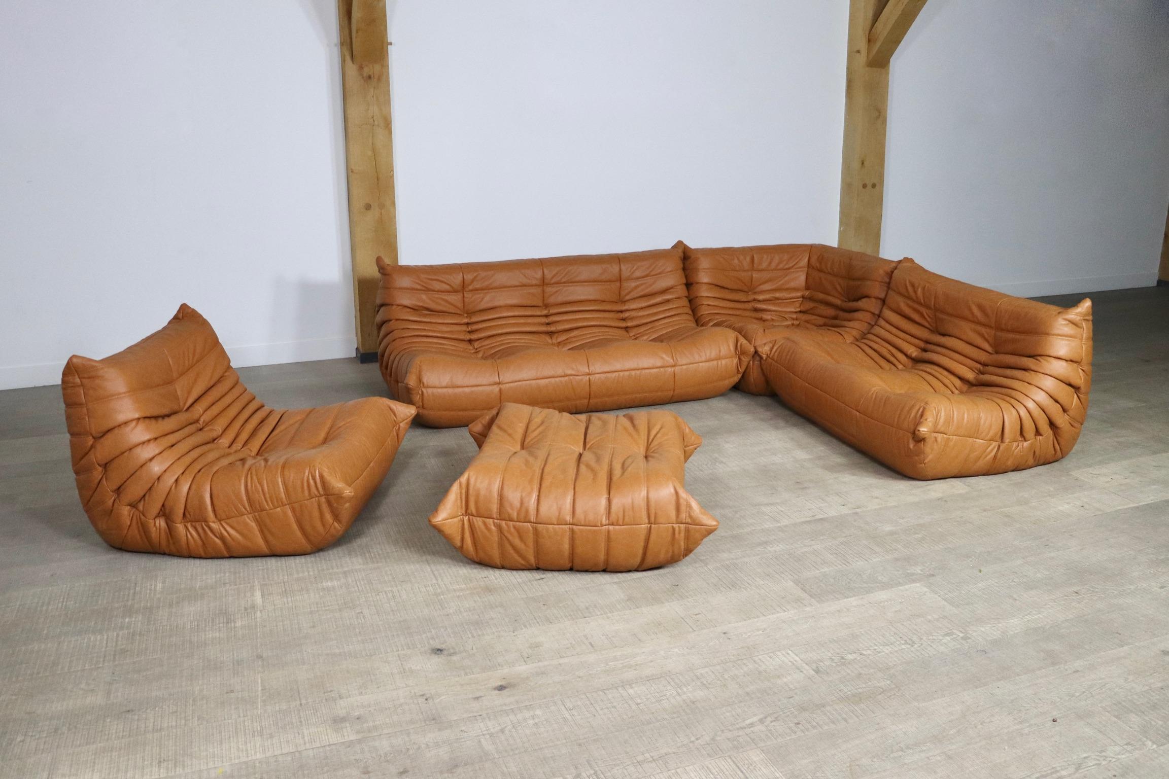 Beautiful cognac leather Togo seating group by Michel Ducaroy for Ligne Roset, 1980s. The entire seating group has the original Ligne Roset logo. The set consists of a 3-seaters, two seater, corner, a lounge chair and an ottoman. The beautiful soft