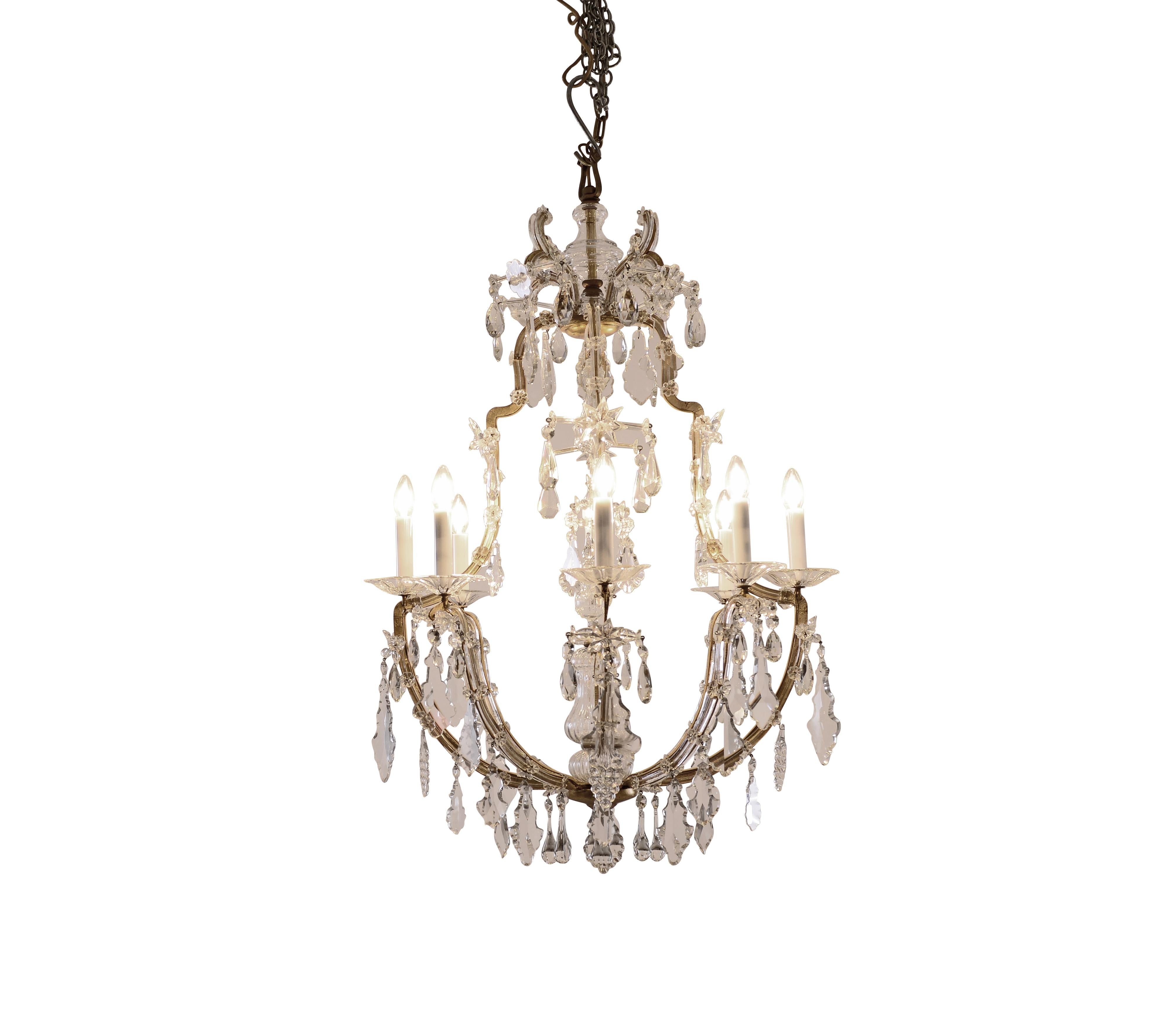 Saloon chandelier crown-shaped Baroque style, hand-wrought metal-frame in gold colour, partly covered with glass, rich in hand-cut glass decoration, eight flames.
Materials & Techniques Notes: bronce hand-wrought, glass bars, hand-cut crystal