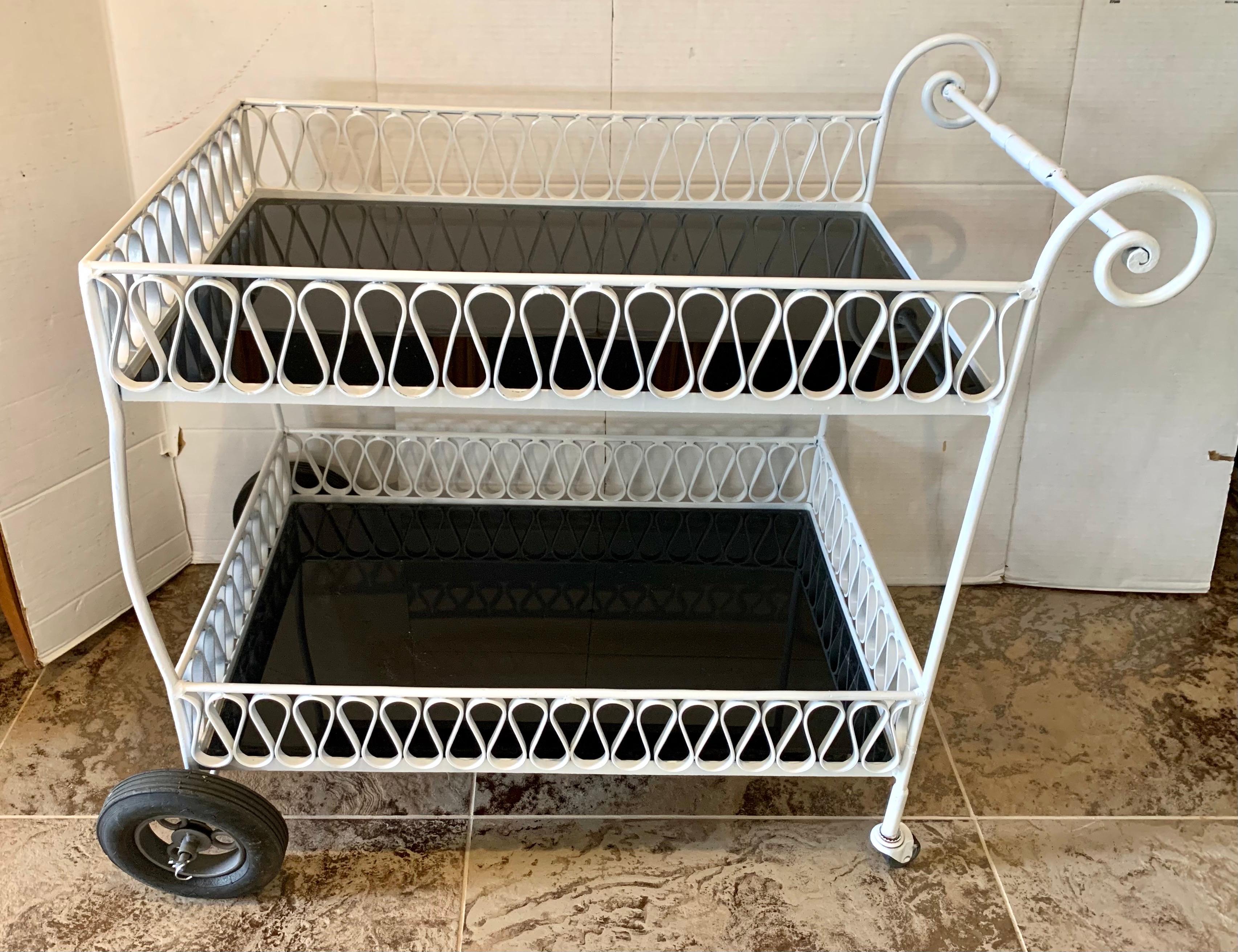 Stunning early Mid-Century Modern Salterini heavy white painted metal rolling bar cart with original black rubber wheels and smoked black glass inset at top and bottom for two-tier bar service. Nothing short of extraordinary! There is age