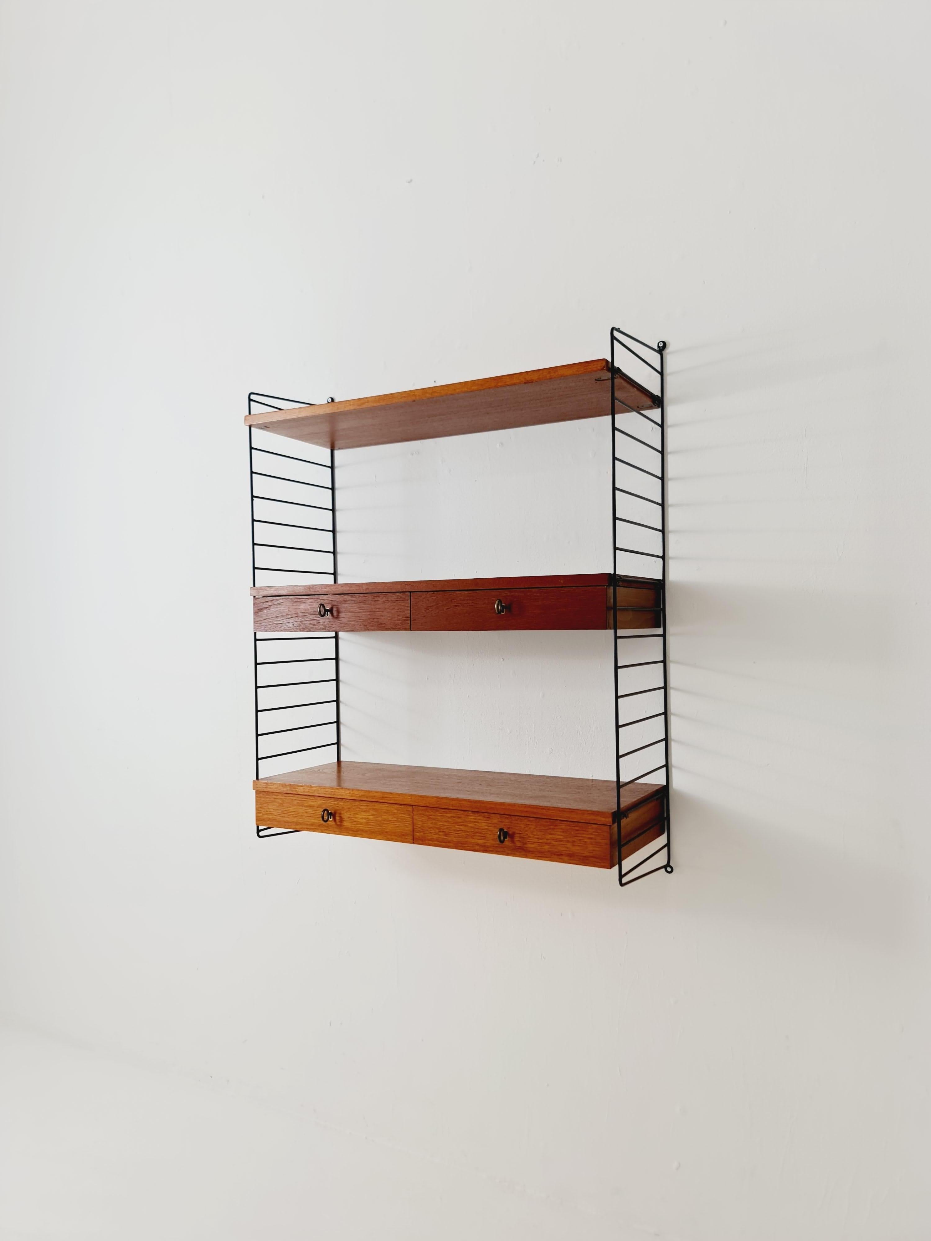 MCM Teak shelving system - consists of black lacquered metal ladders, from string Stockholm. 


The respective elements are made of teak (veneer). In addition to shelves, lockable compartments, and space for books, the system has a desk with