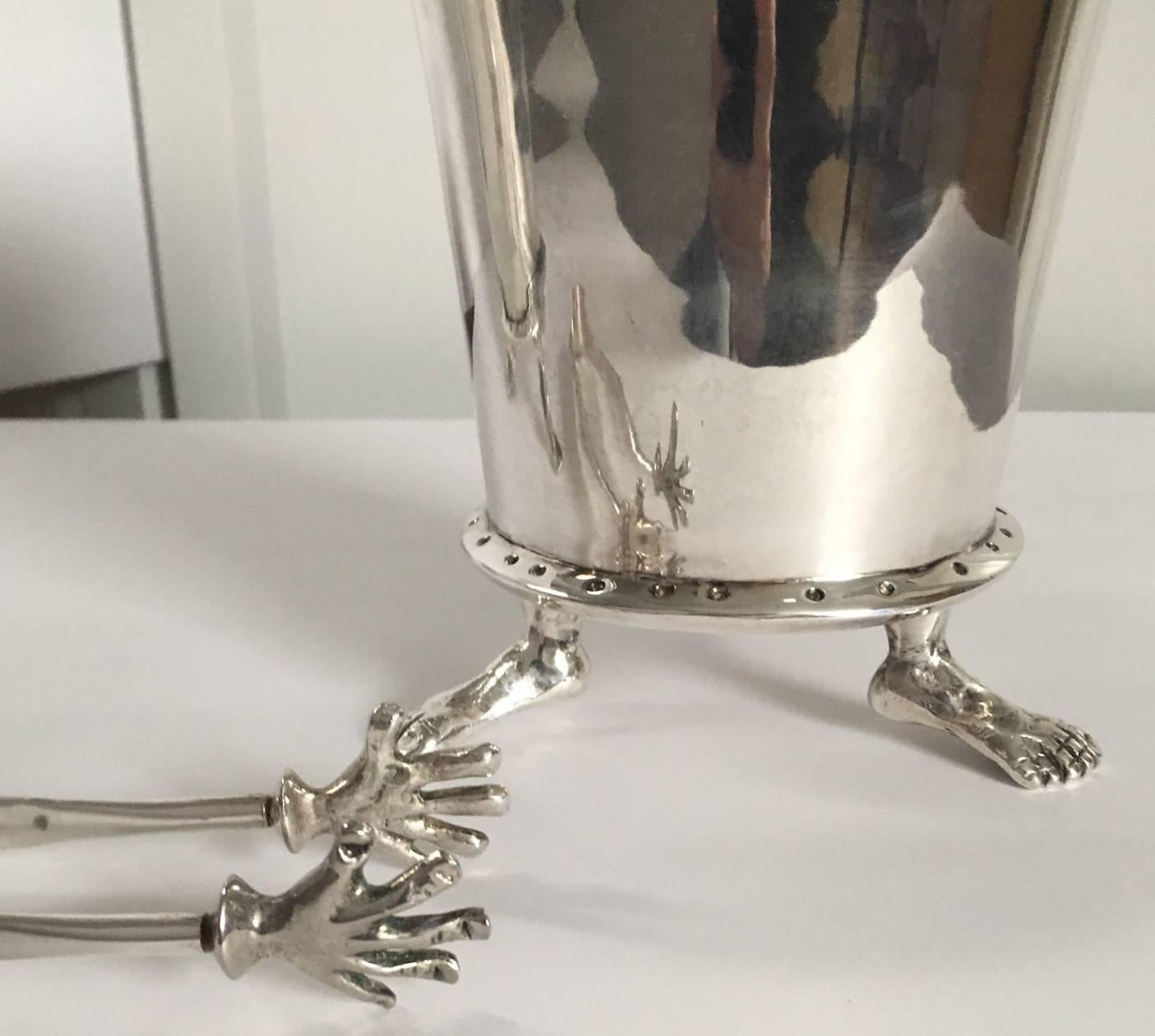 Original 1990s production of the hands and feet collection by renowned metal artisan Michael Aram. Offered are two silver plated footed ice buckets with one pair of tongs. A later and lesser detailed version of Aram's hands and feet collection was